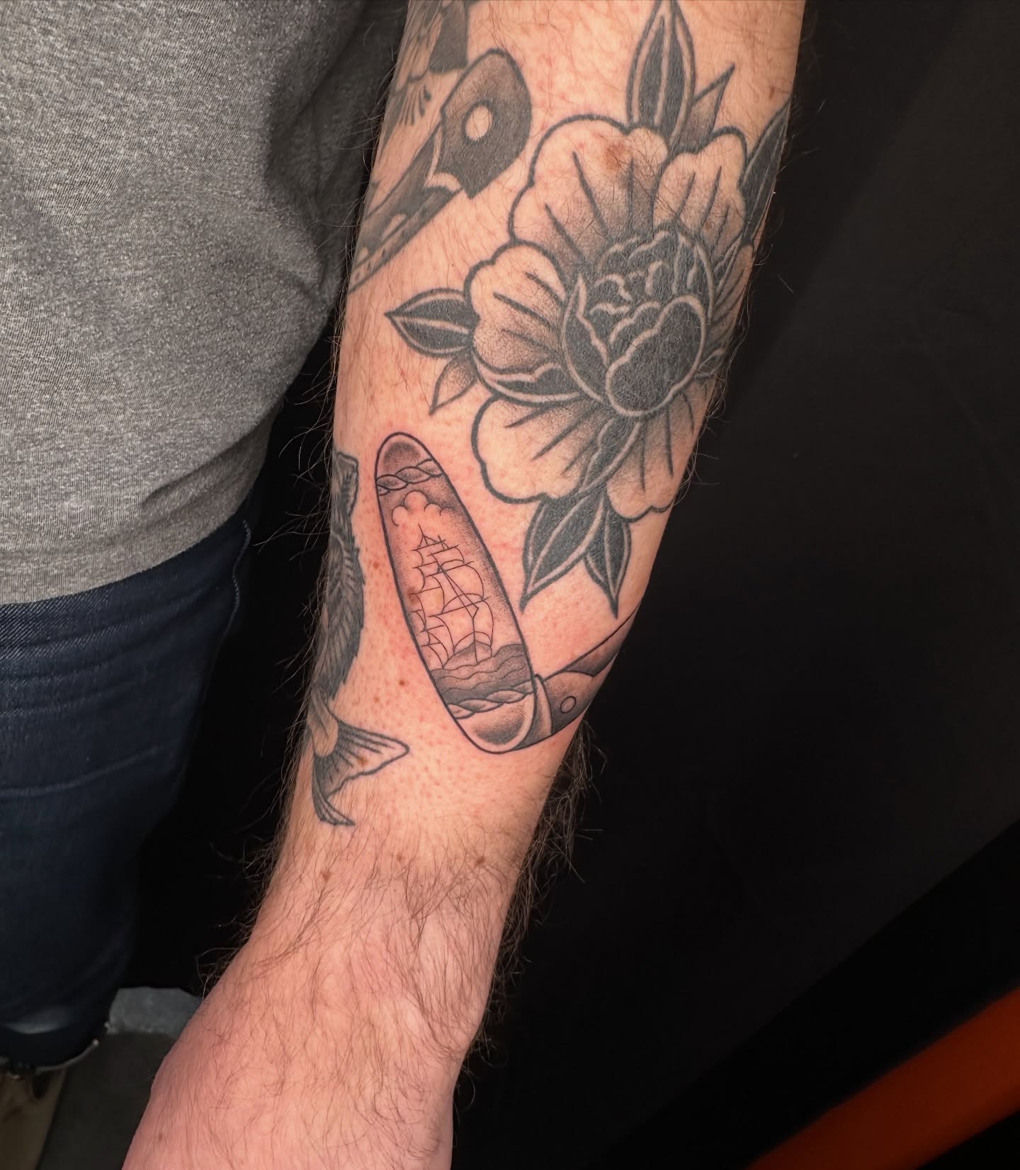 Ship and flower black and grey tattoo on the forearm by Hail Chaney, Somerville, Massachusetts