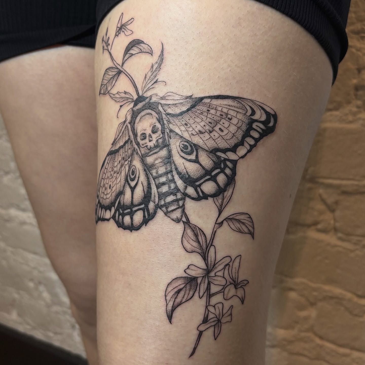 Butterfly with skull realism tattoo on the thigh by Sydney Gallucci