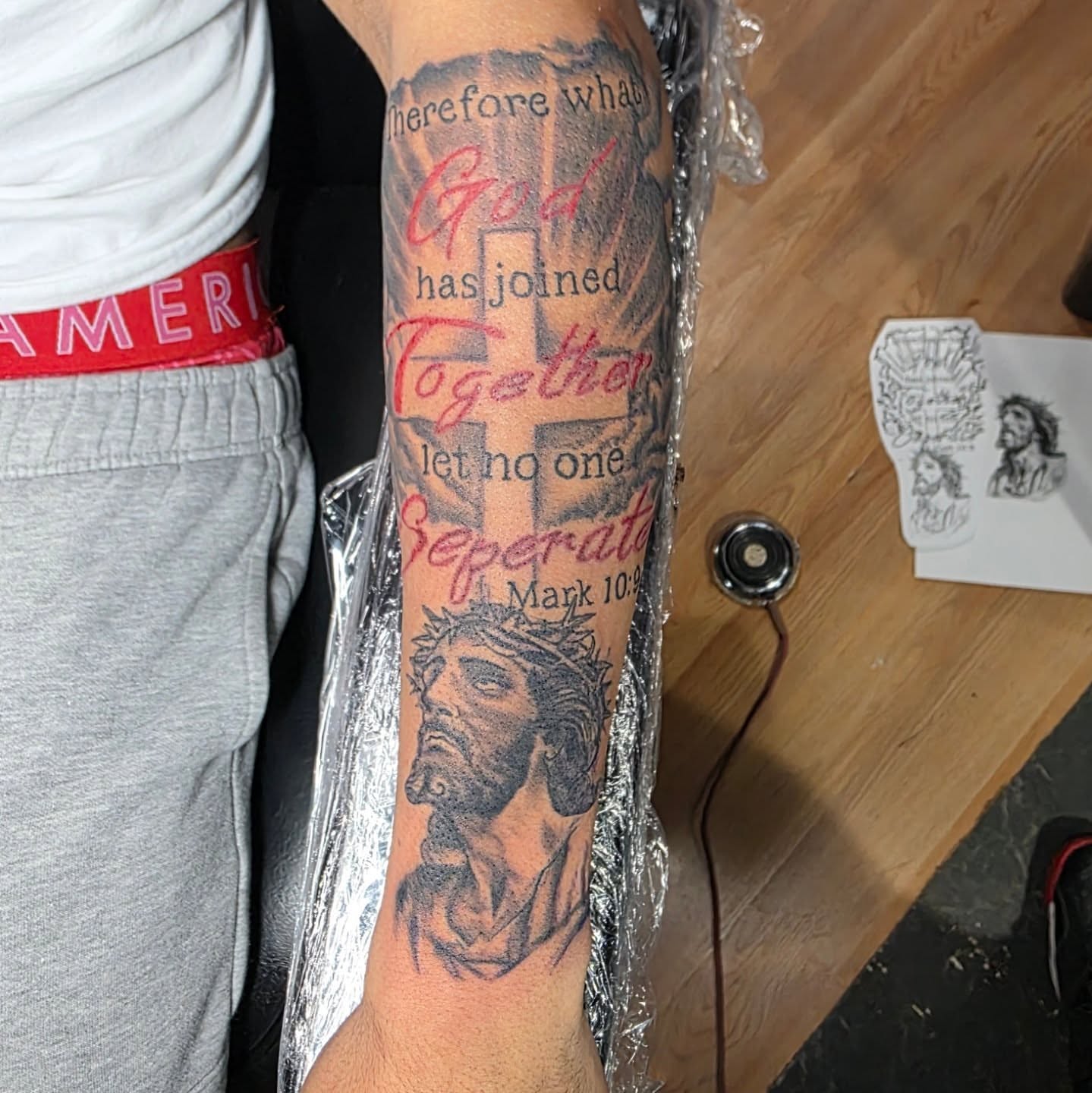 Religious text black and grey tattoo on the forearm by Rusty Williams