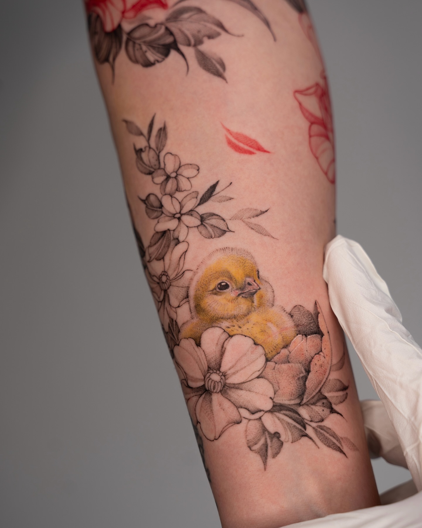 Chick and flowers realism tattoo on the forearm by Tri
