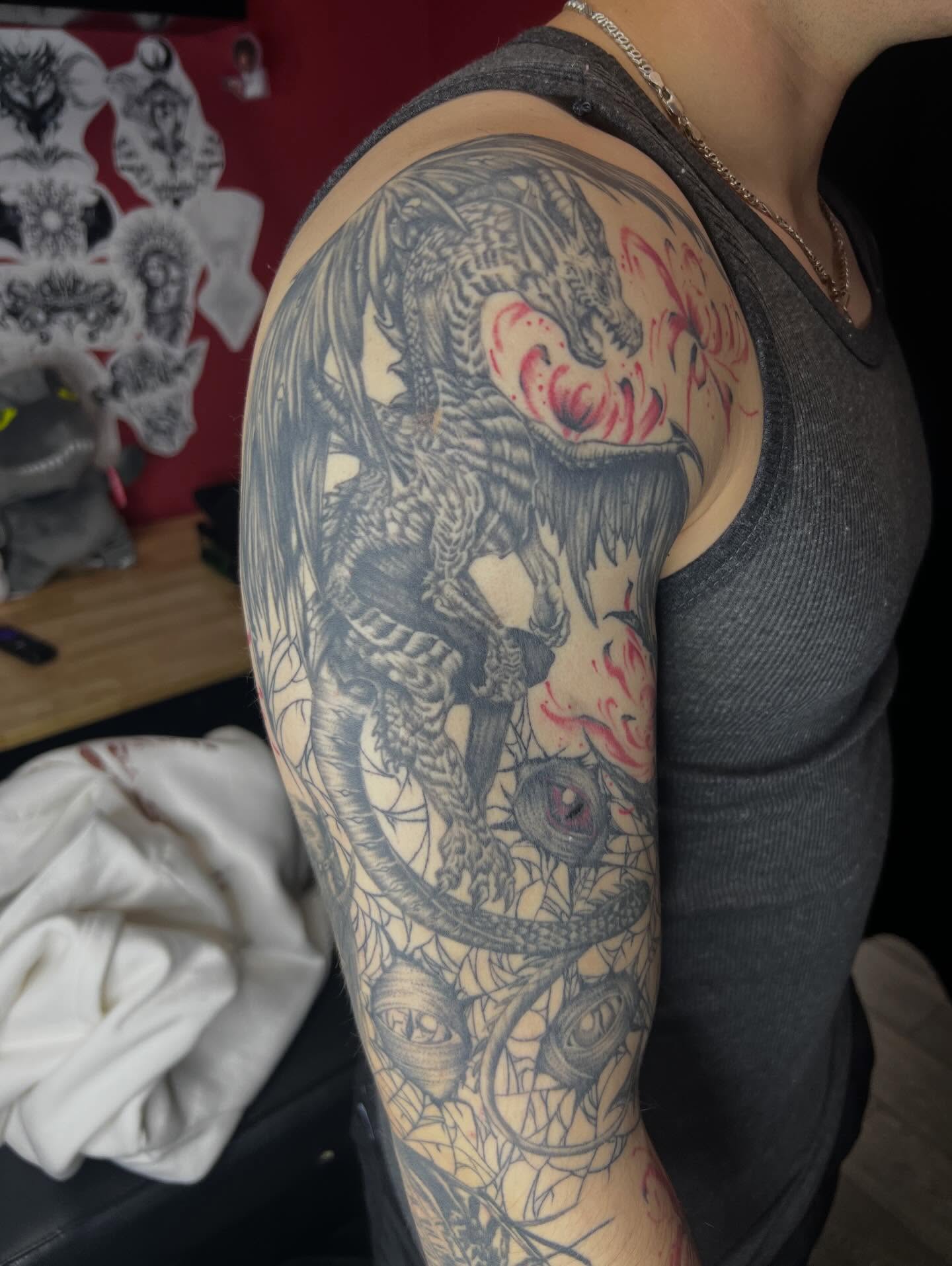 Dragon black and grey tattoo on the upper arm by Dark Luna Tattoos LLC