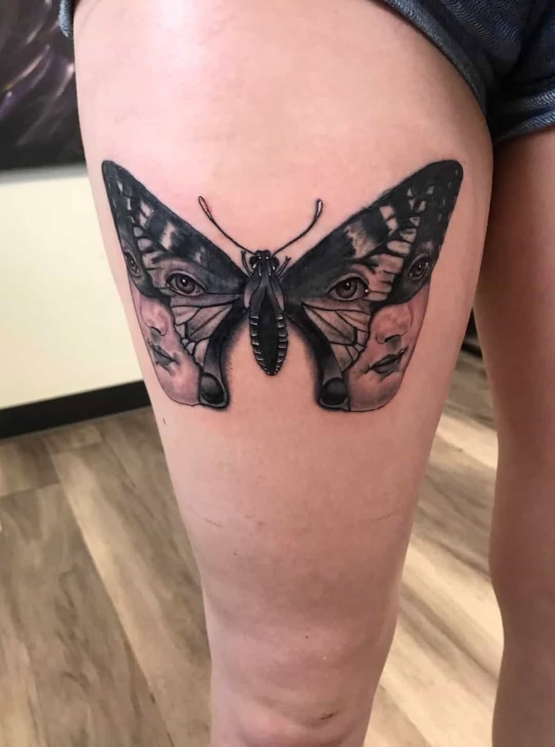 Butterfly with faces fine line tattoo on the thigh by Sk Pierce
