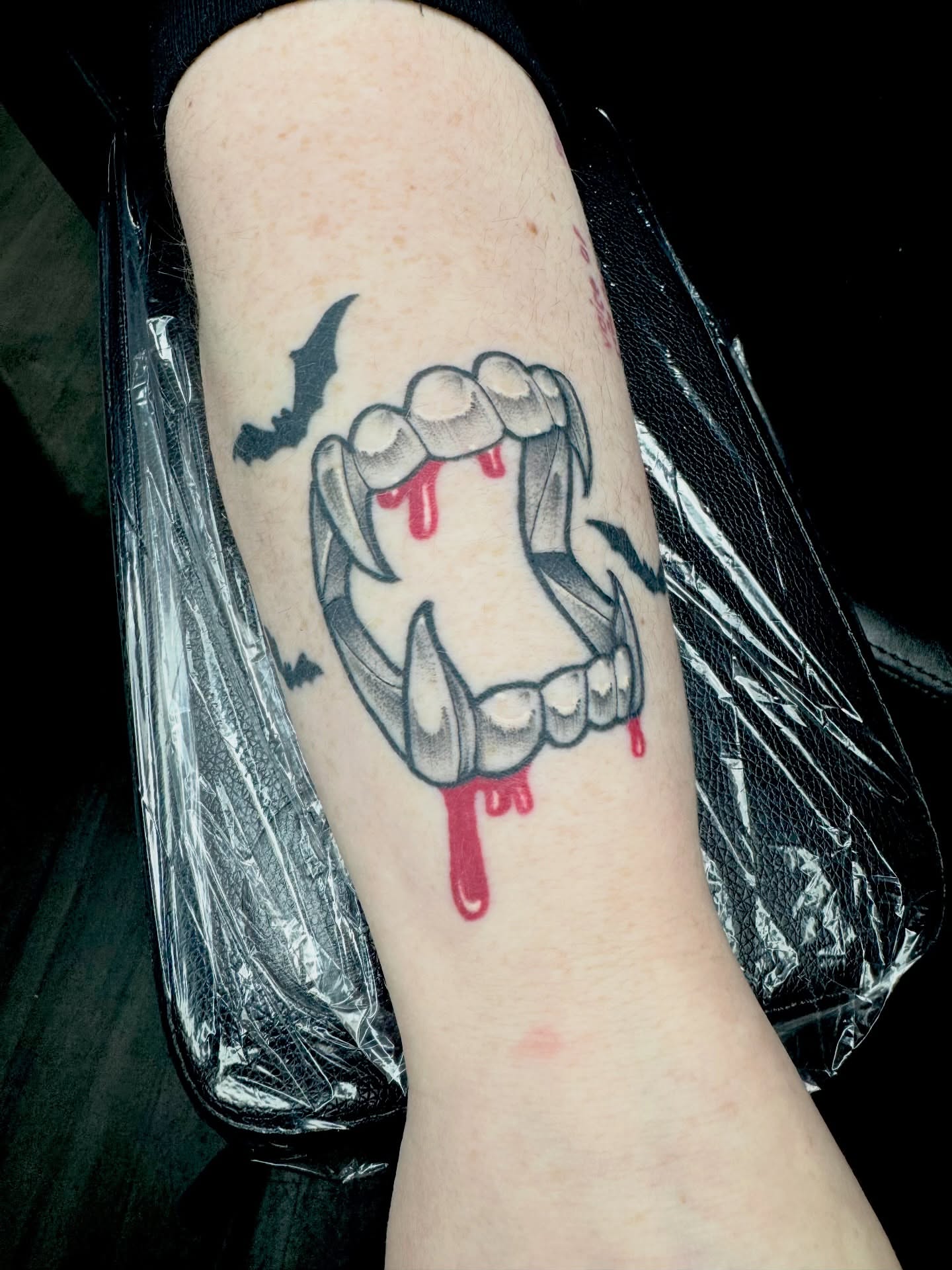 Fangs and blood black and grey tattoo on the forearm by Brett Brown