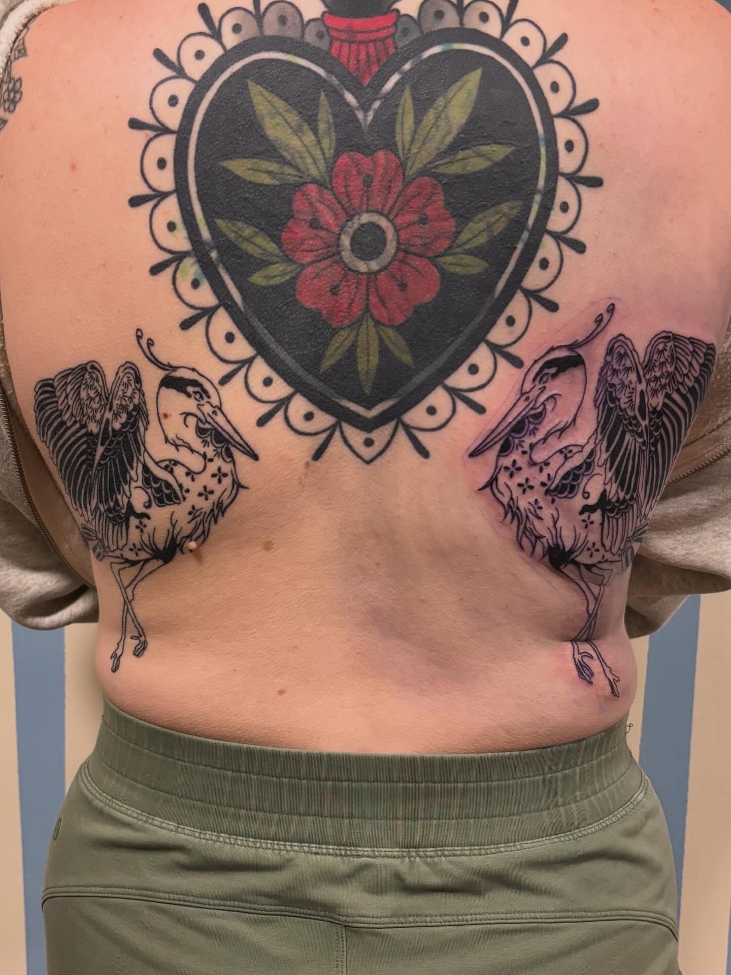 Heart with floral design American traditional tattoo on the back by Ashley Ellerman