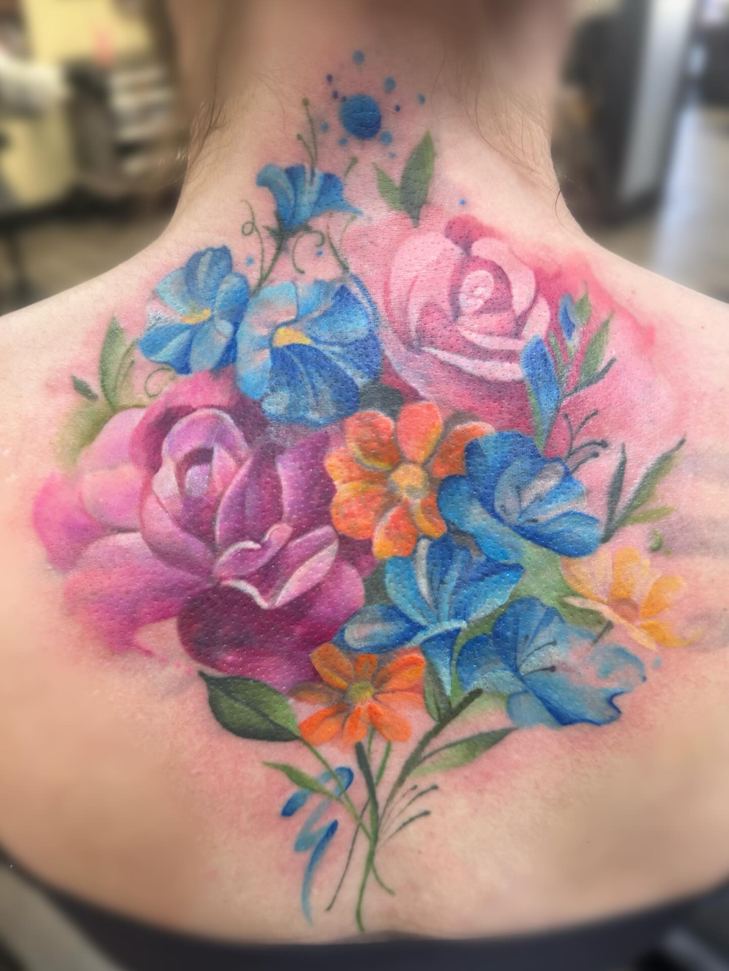 Flower bouquet watercolor tattoo on the back by Elly Bordwell