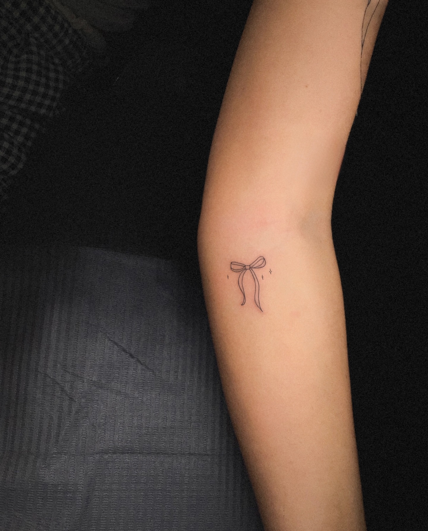 Bow fine line tattoo on the forearm by Nicole