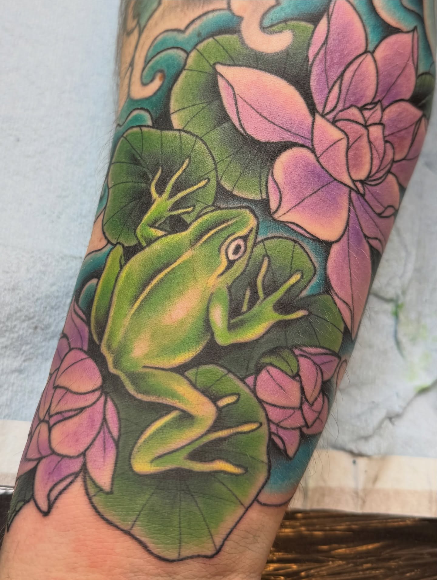 Frog and lotus realism tattoo on the forearm by Anna Wall