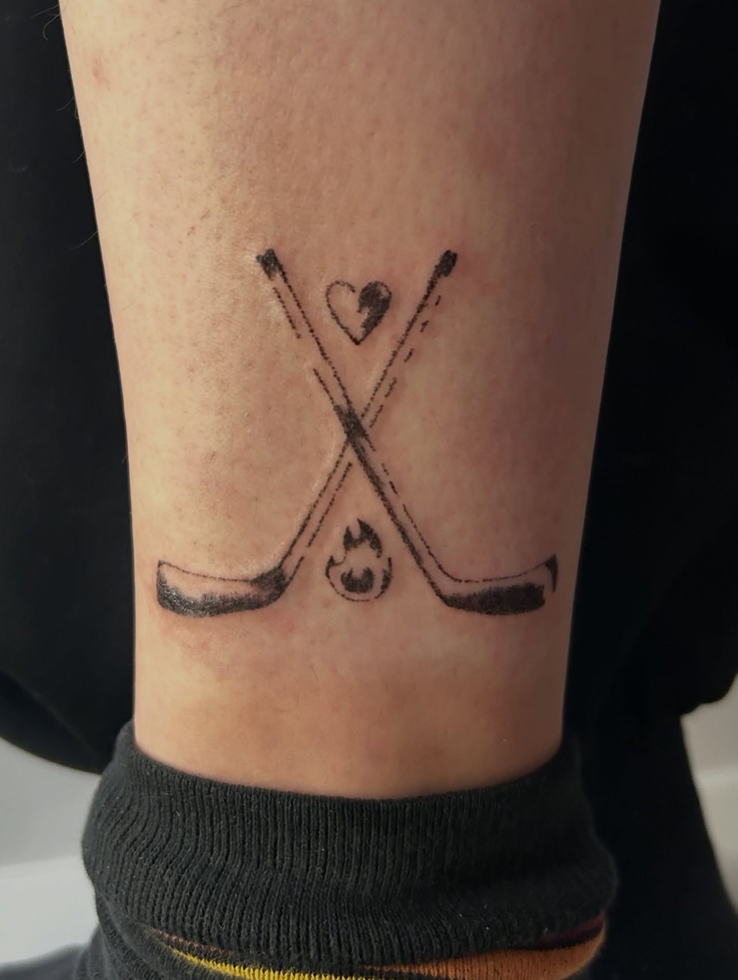 Hockey sticks and heart minimalist tattoo on the forearm by wanderfernfairy