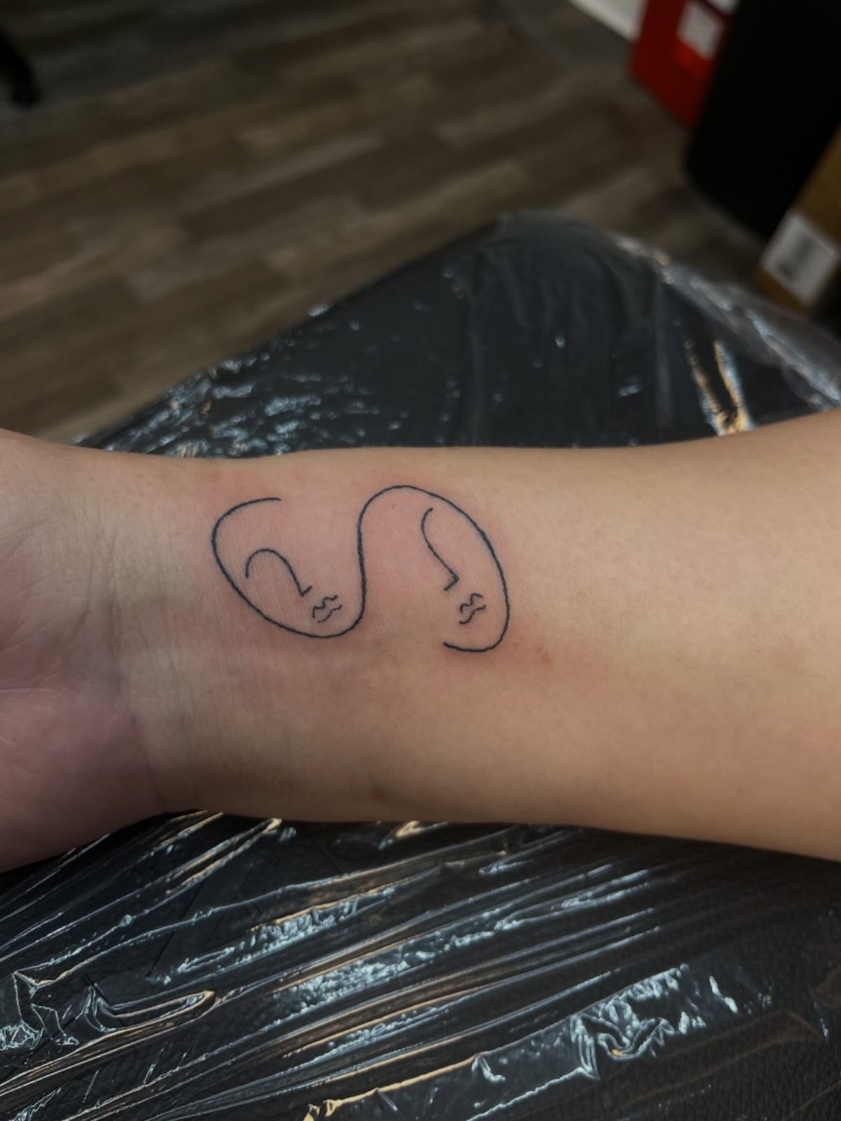Two faces minimalist tattoo on the forearm by XoXandrea.Ink, Kansas City, Missouri