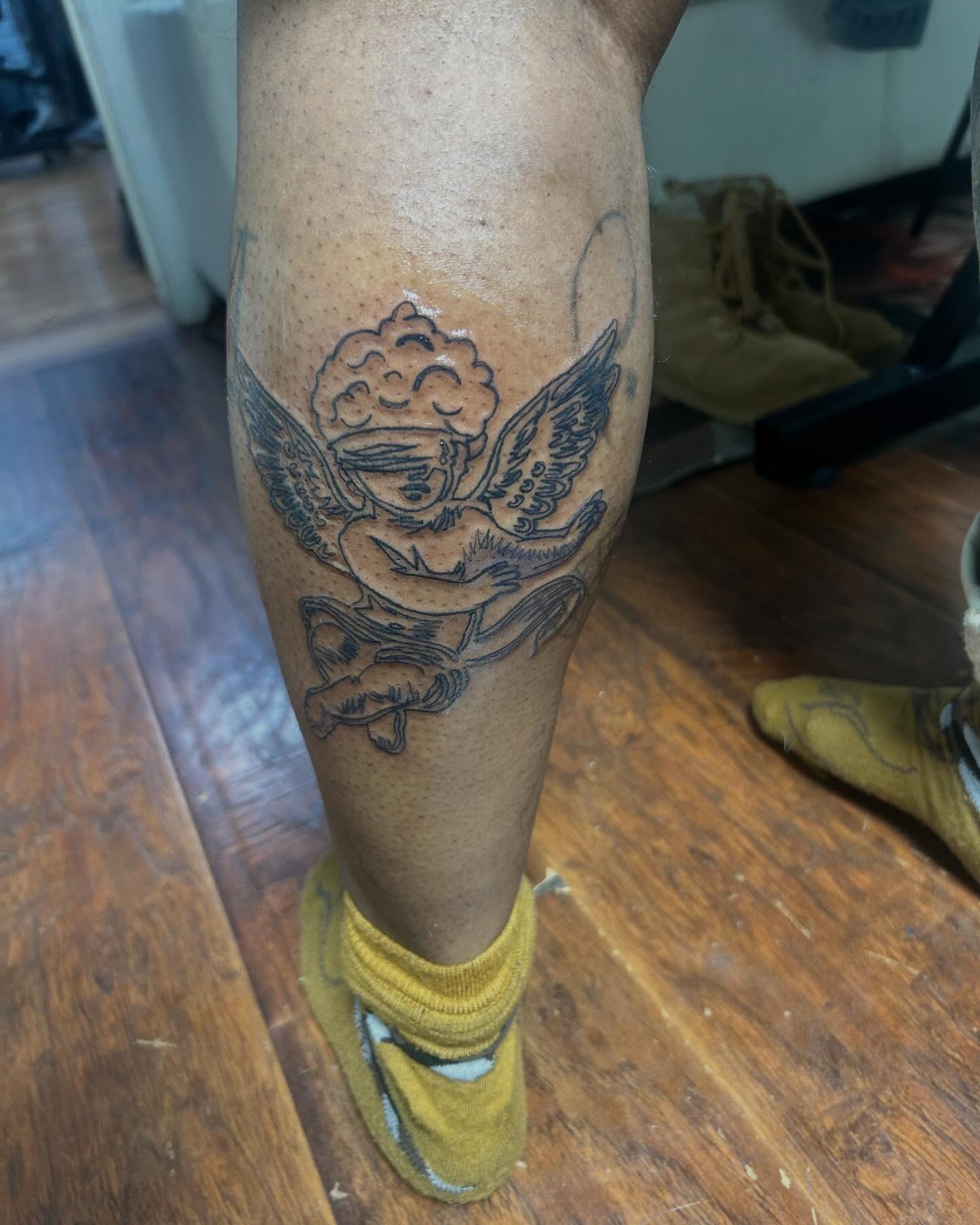 Cherub black and grey tattoo on the calf by Jae the artist🫡