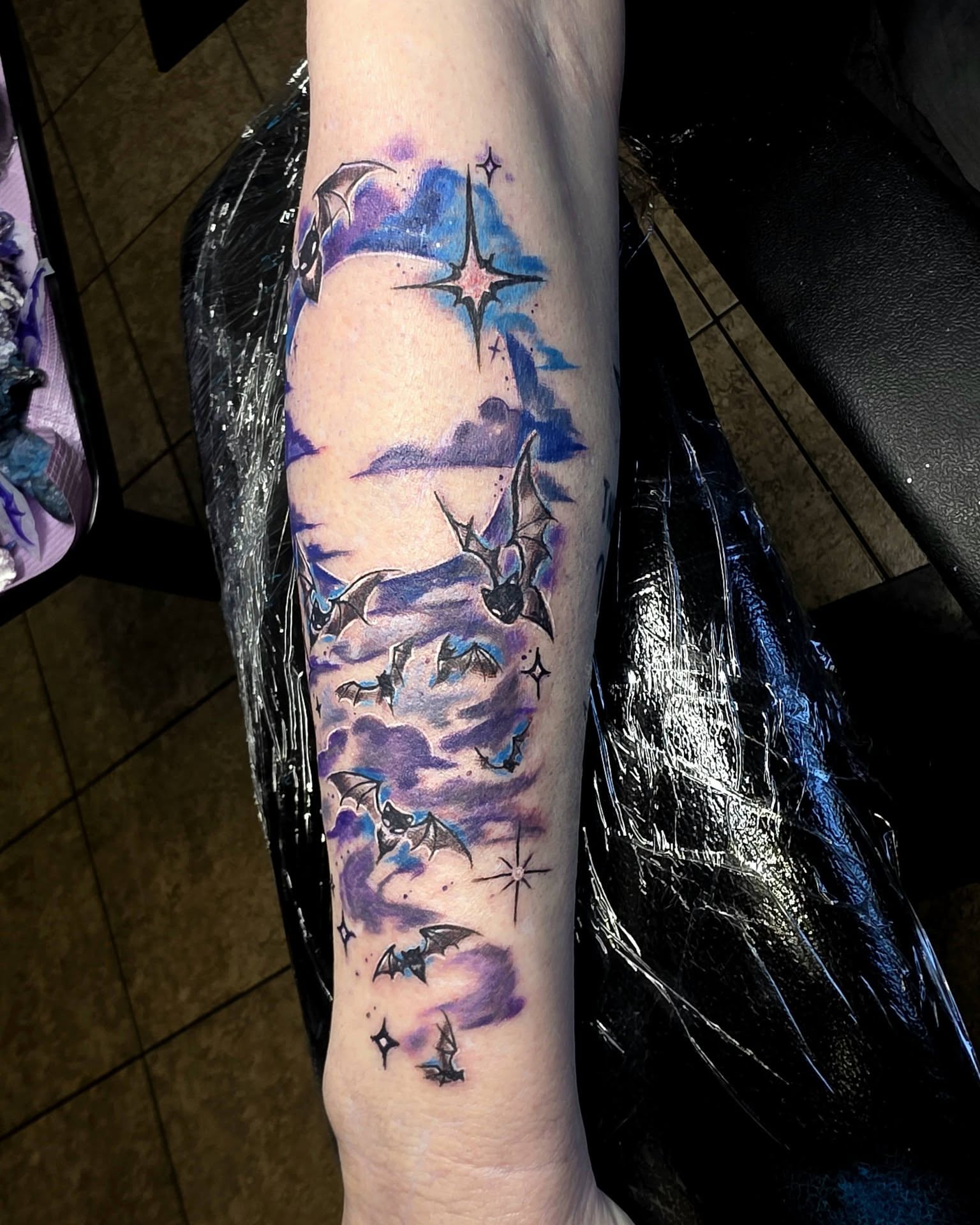 Night sky with bats watercolor tattoo on the forearm by Jessica DarkRabbit