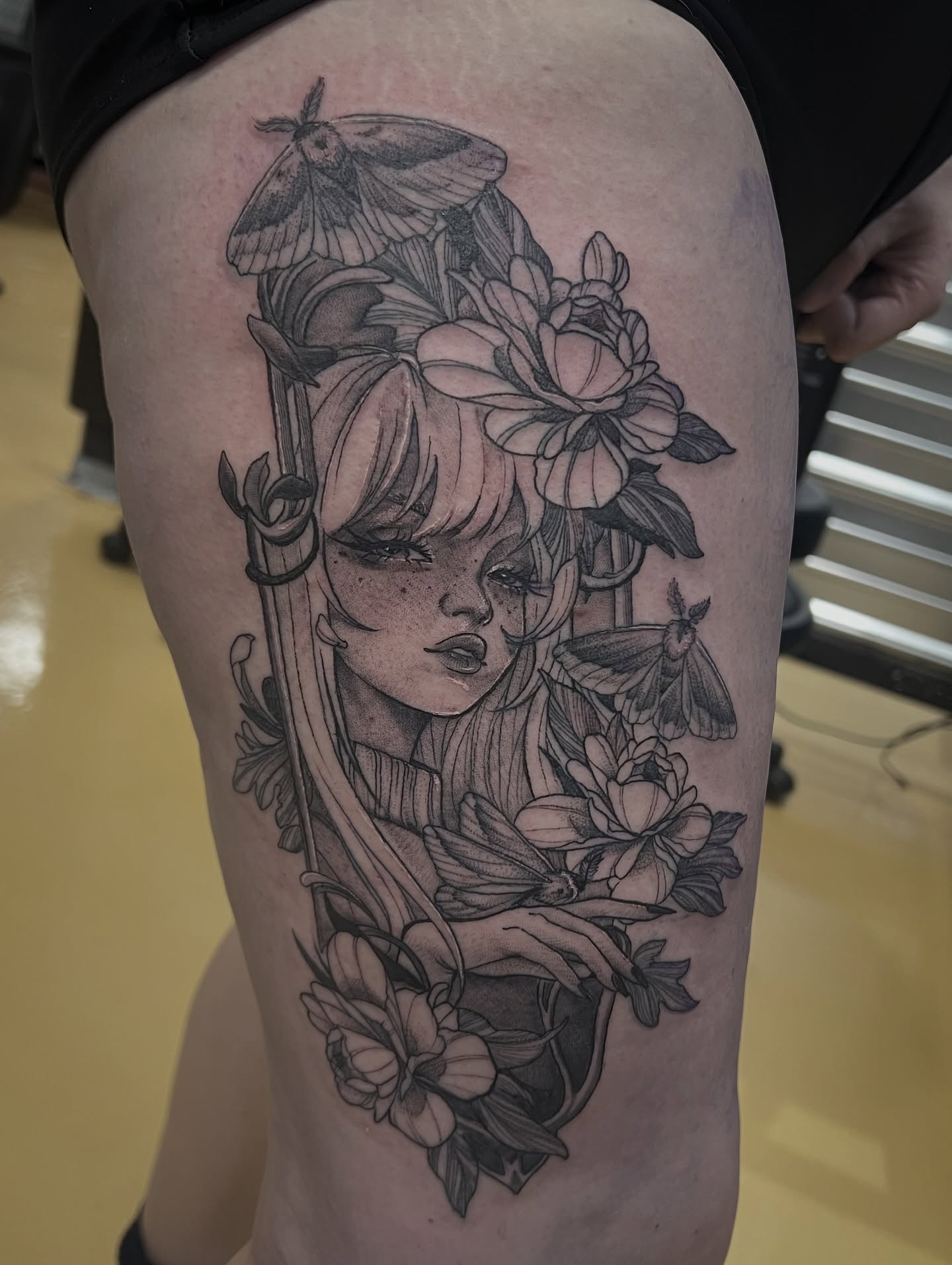 Woman with flowers and moths realism tattoo on the thigh by Kat