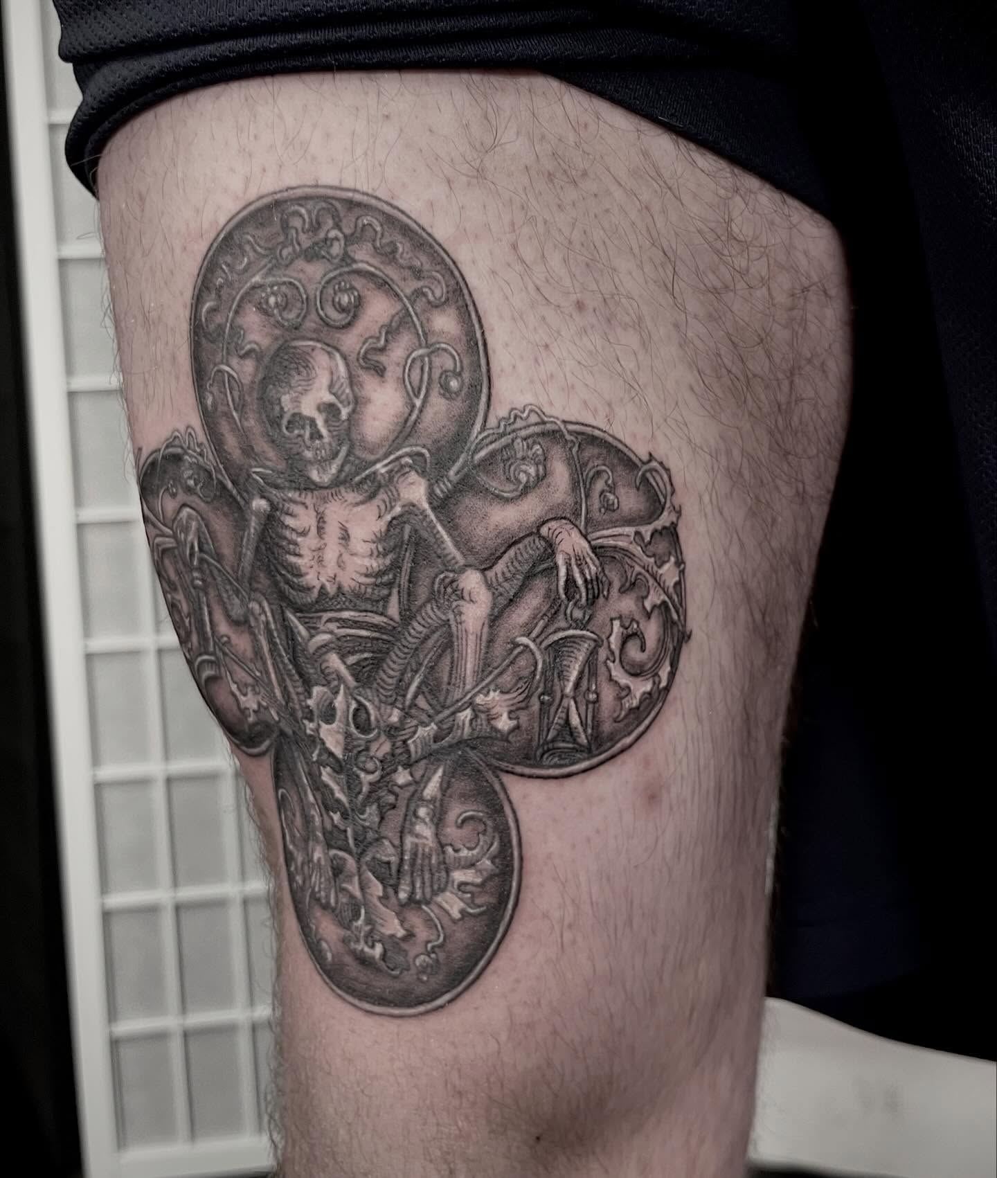 Skeleton and ornate shield realism tattoo on the thigh by Tattoo Artist