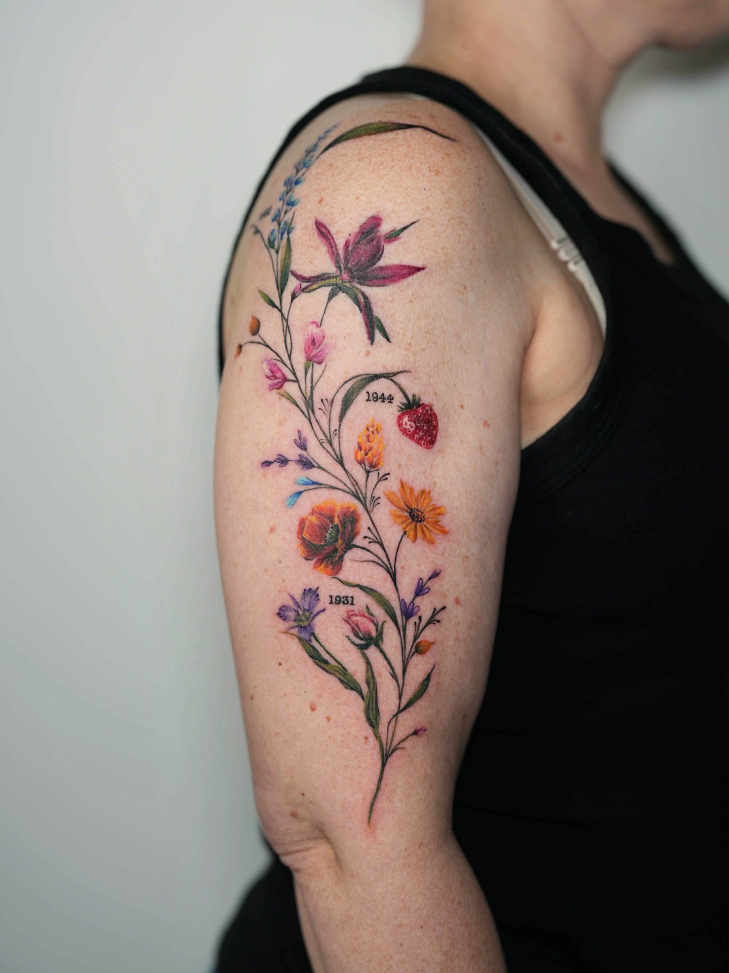 Botanical bouquet watercolor tattoo on the upper arm by Henry