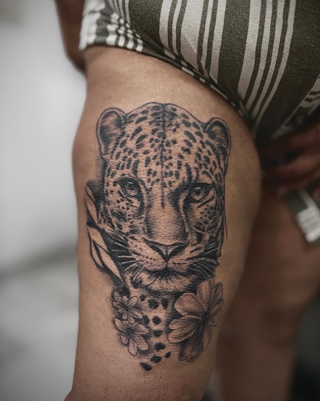 Leopard face with flowers realism tattoo on the thigh by Mauricio gois