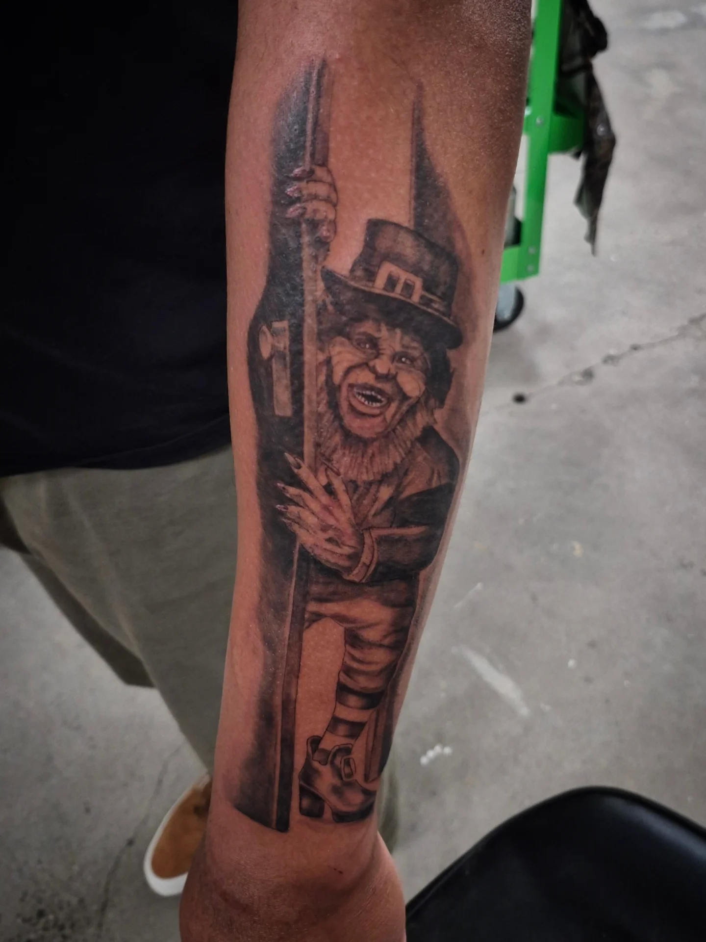 Clown with cane black and grey tattoo on the forearm by Lydia Kiley