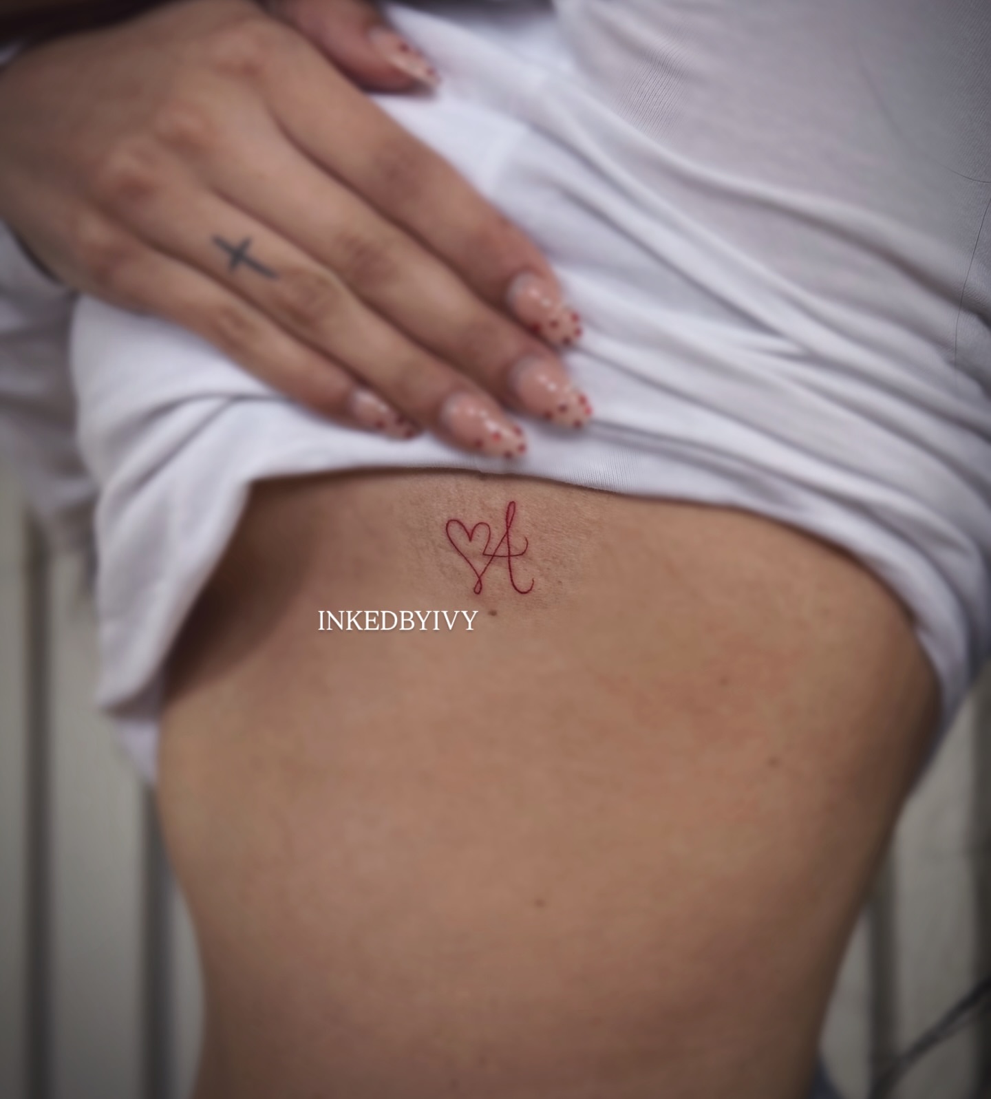 Heart and letter A fine line tattoo on the thigh by IVY