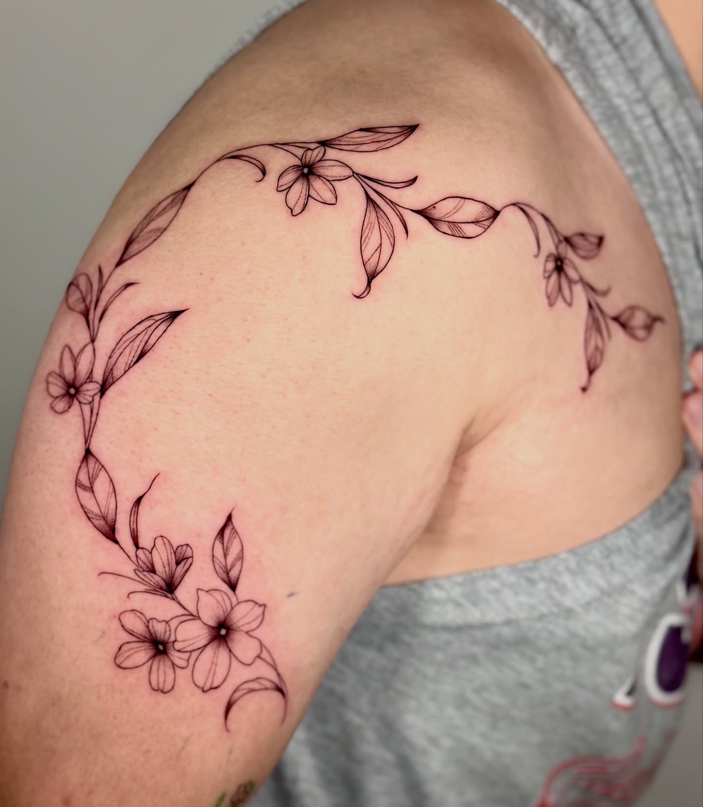 Floral wreath fine line tattoo on the shoulder by Orca