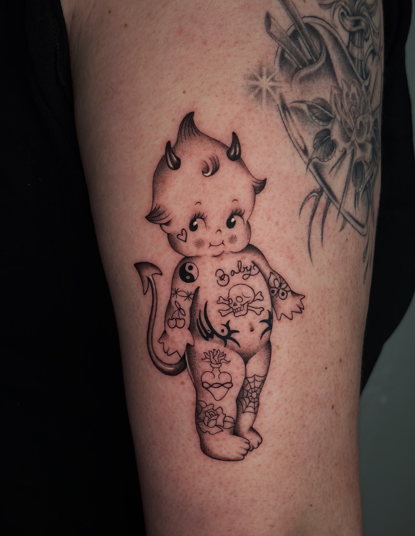 Baby with horns black and grey tattoo on the forearm by Lauryn Jenesis