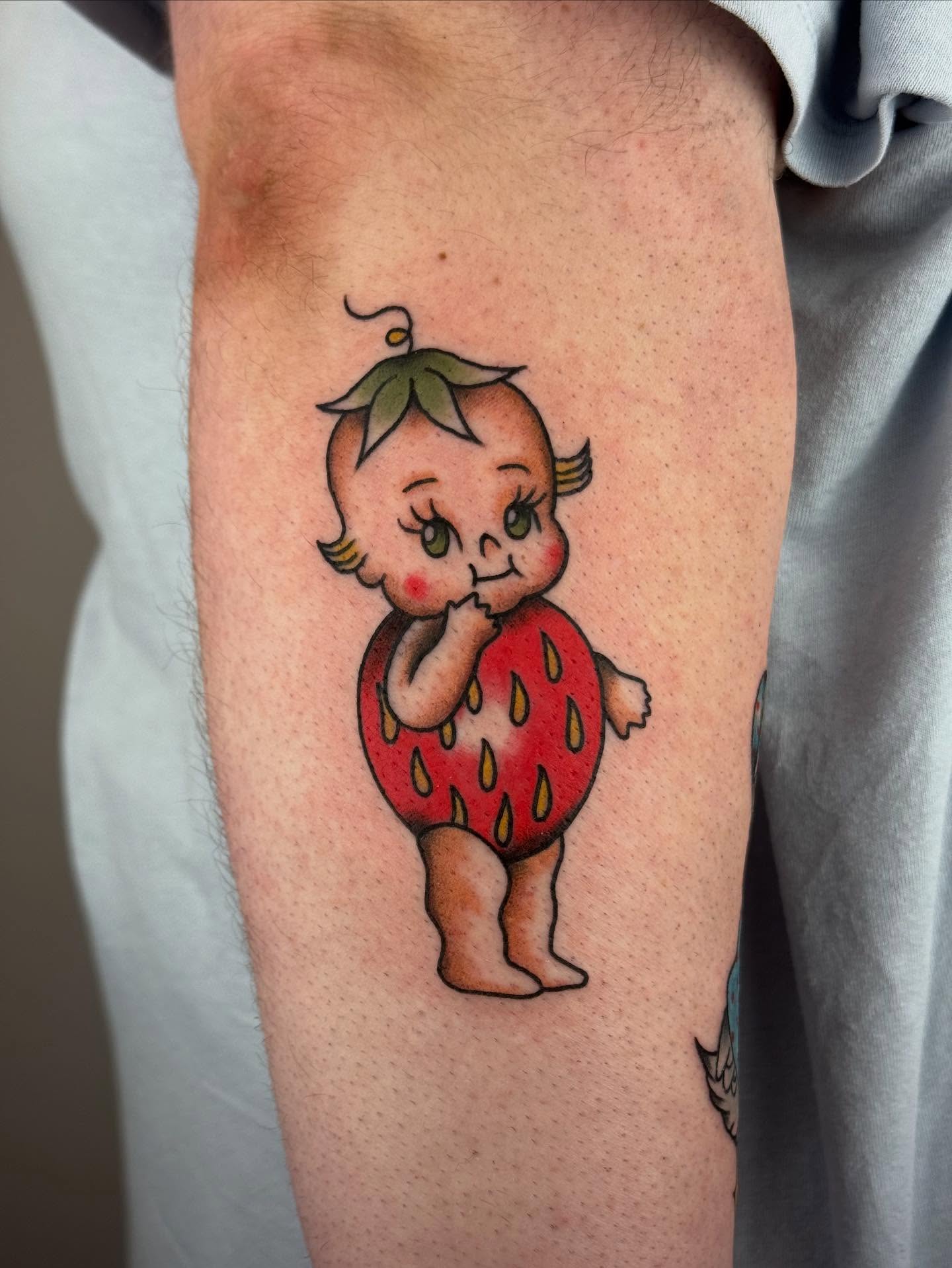 Baby in strawberry costume American traditional tattoo on the forearm by π©πͺπ¬