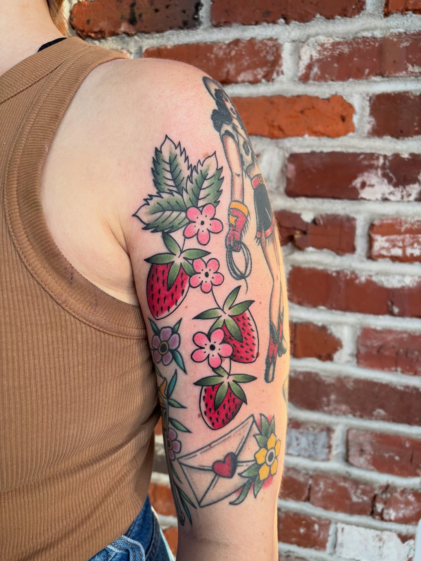 Strawberries and flowers American traditional tattoo on the upper arm by Malia Clark
