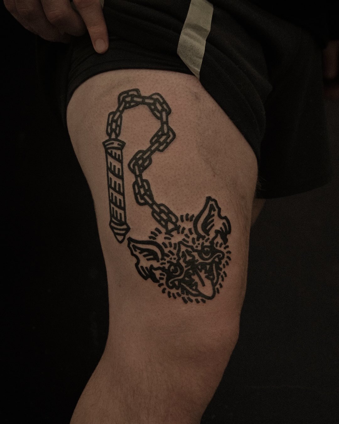 Demon head with chain black and grey tattoo on the thigh by ashley blyght