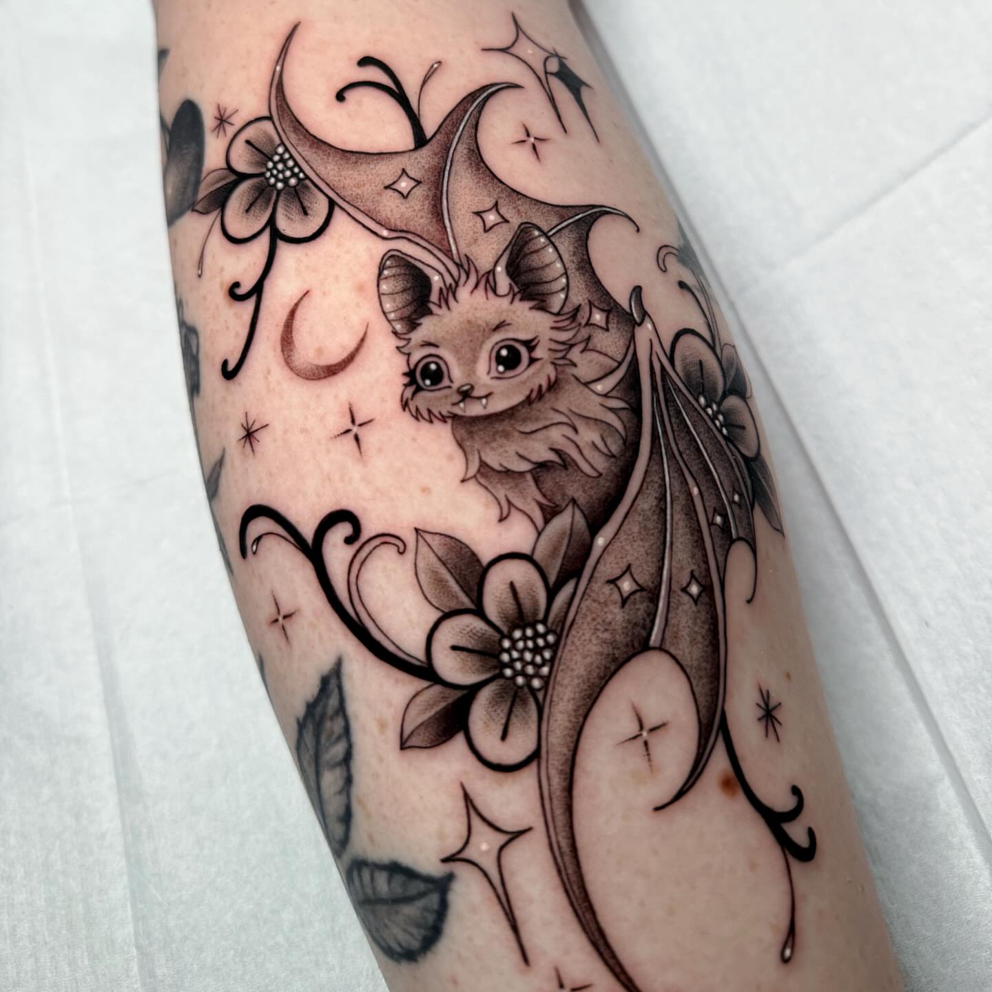 Bat and floral black and grey tattoo on the forearm by Alexia
