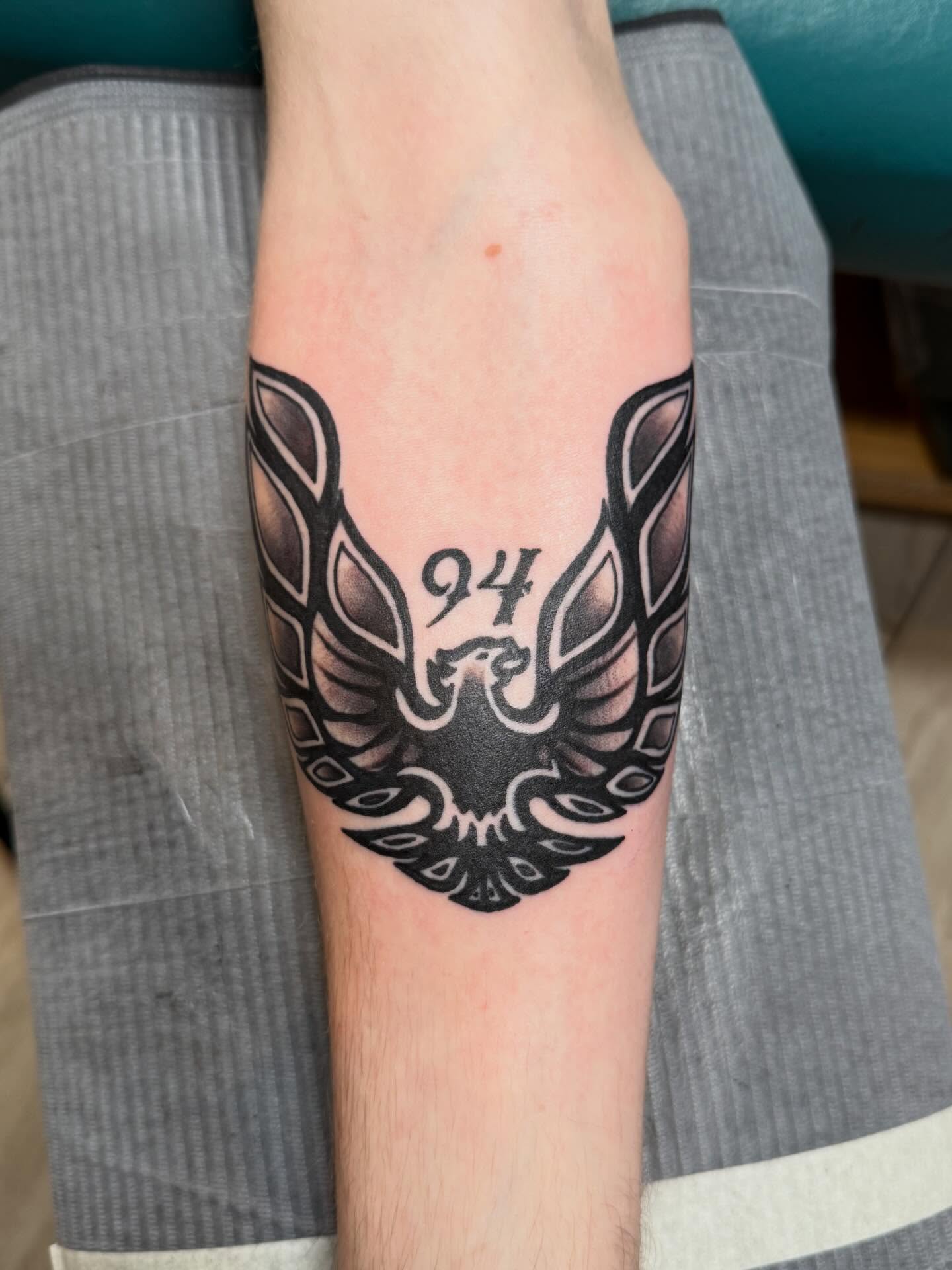 Winged emblem black and grey tattoo on the forearm by Bill Crawford, Plymouth, Michigan