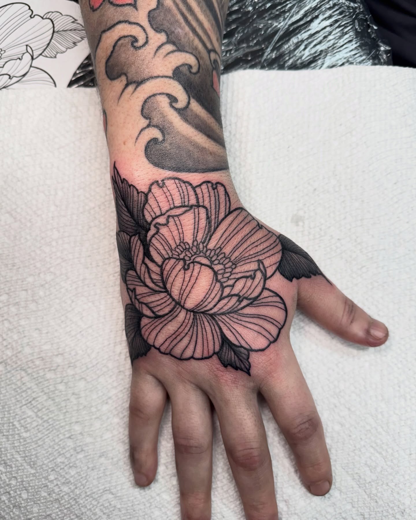Lotus flower black and grey tattoo on the hand by Eden Allen