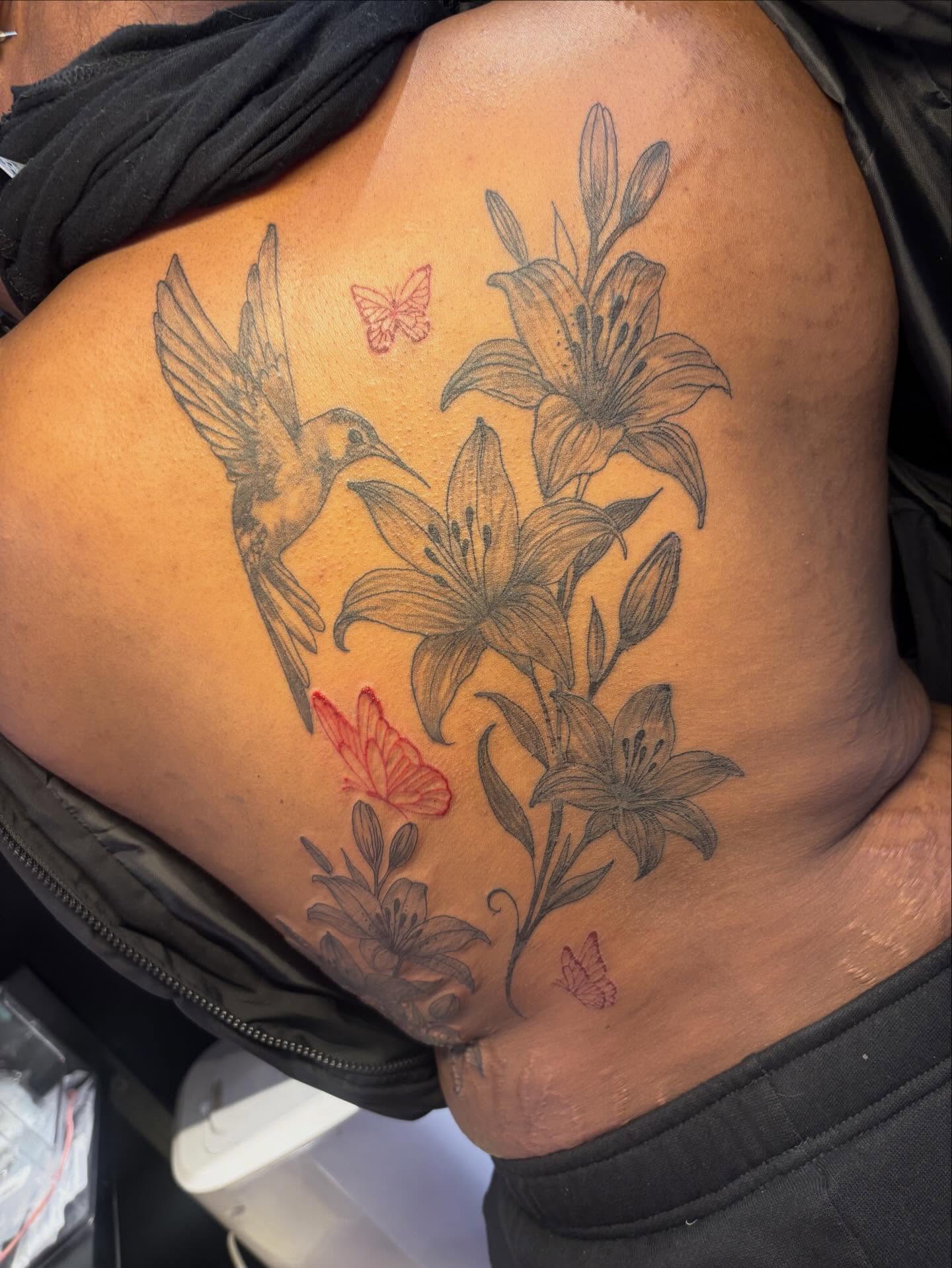 Lilies and hummingbird black and grey tattoo on the shoulder by addicted222inkk🎨