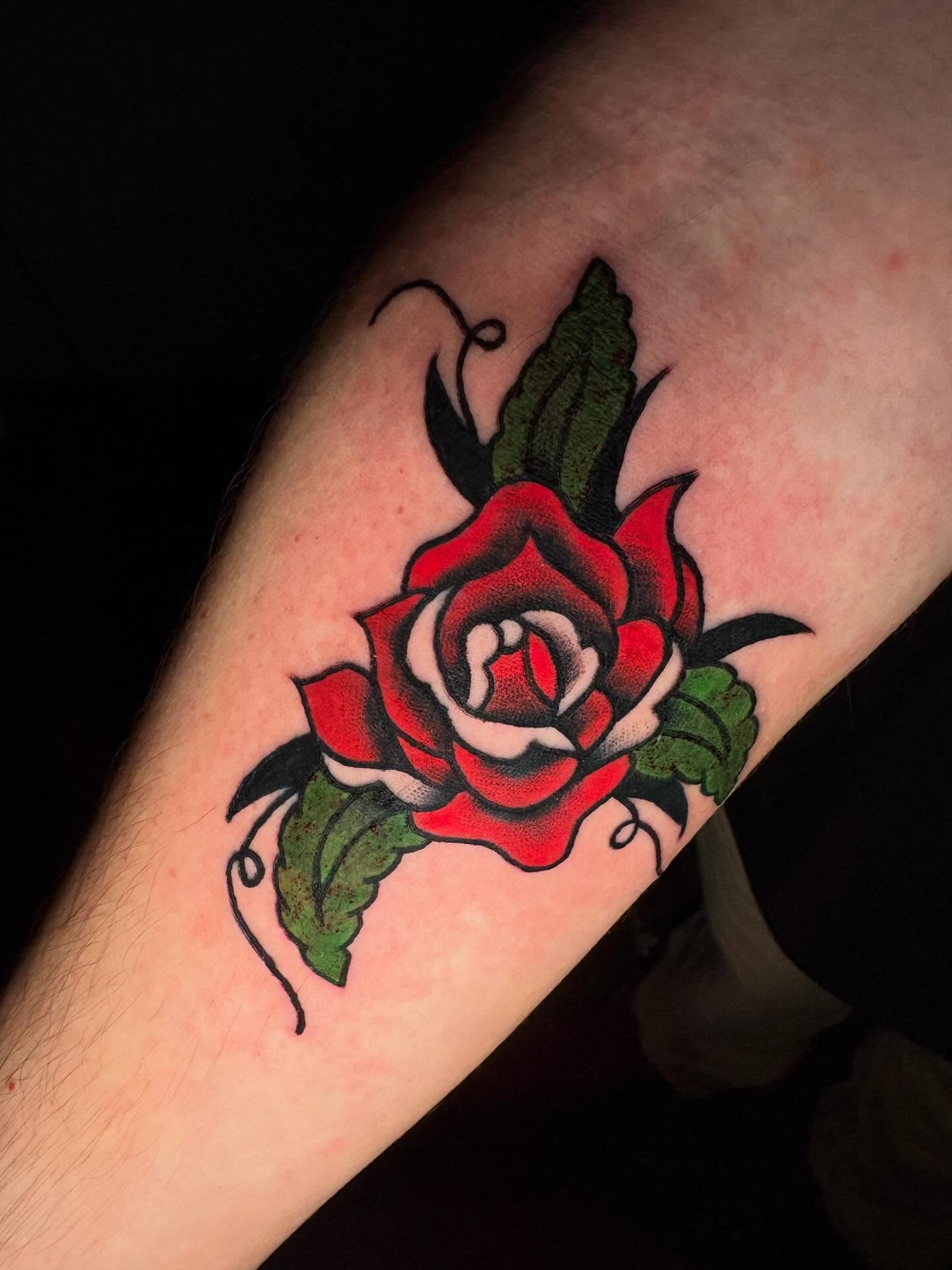 Red rose American traditional tattoo on the forearm by Jenna Clayton
