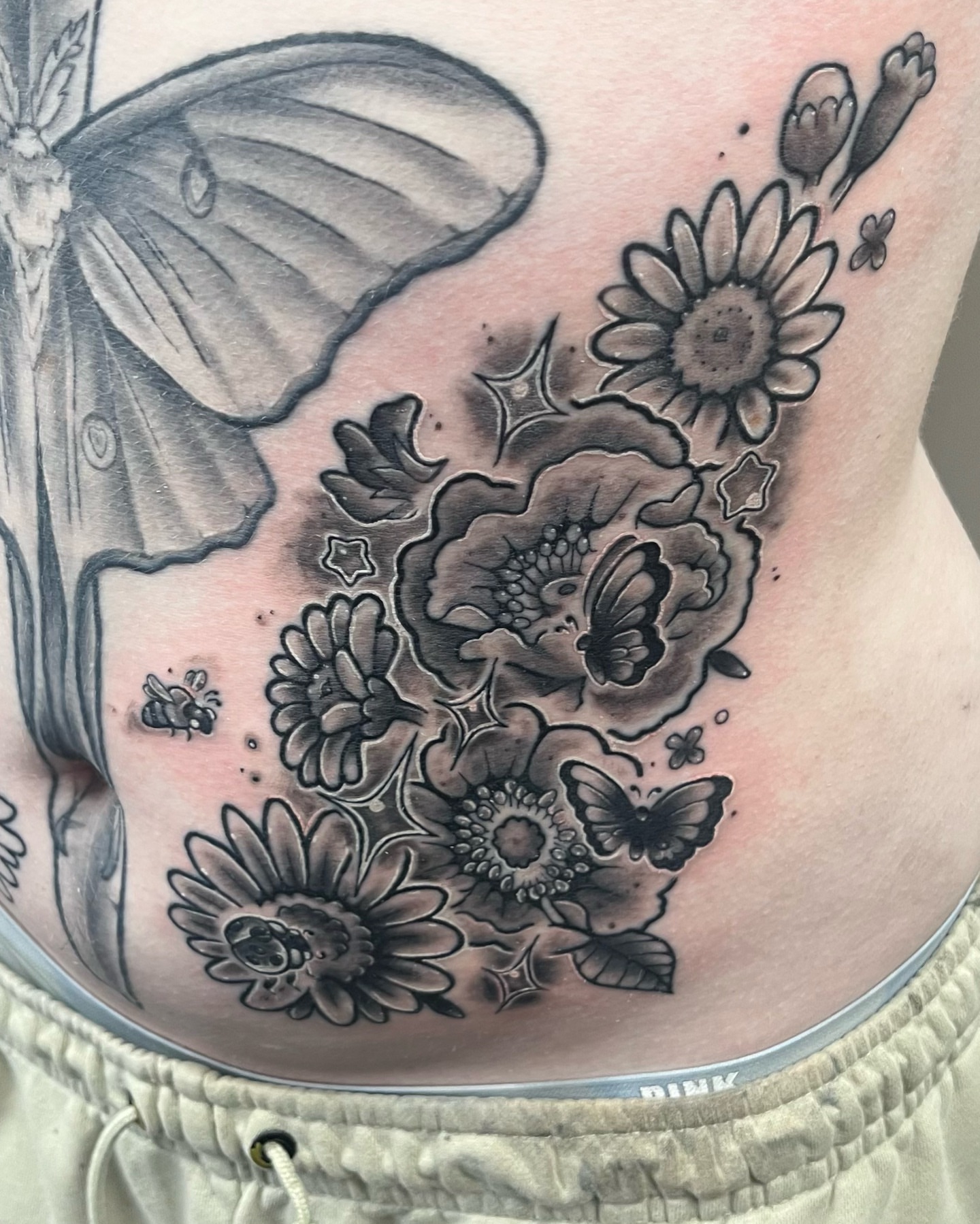 Flowers and butterflies black and grey tattoo on the torso by Chloe ‘baby’ Martin