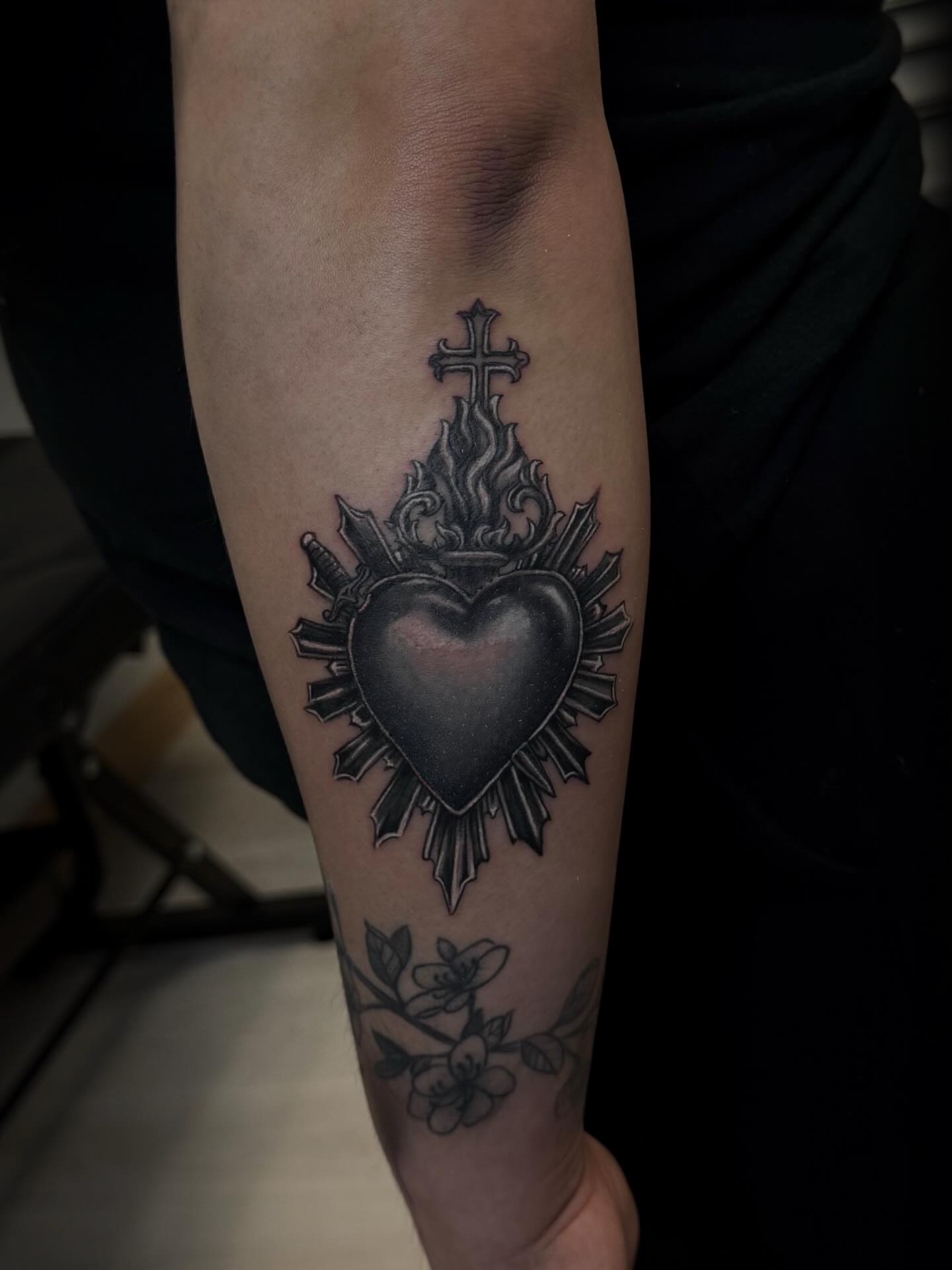 Heart with cross and swords black and grey tattoo on the forearm by Gigi