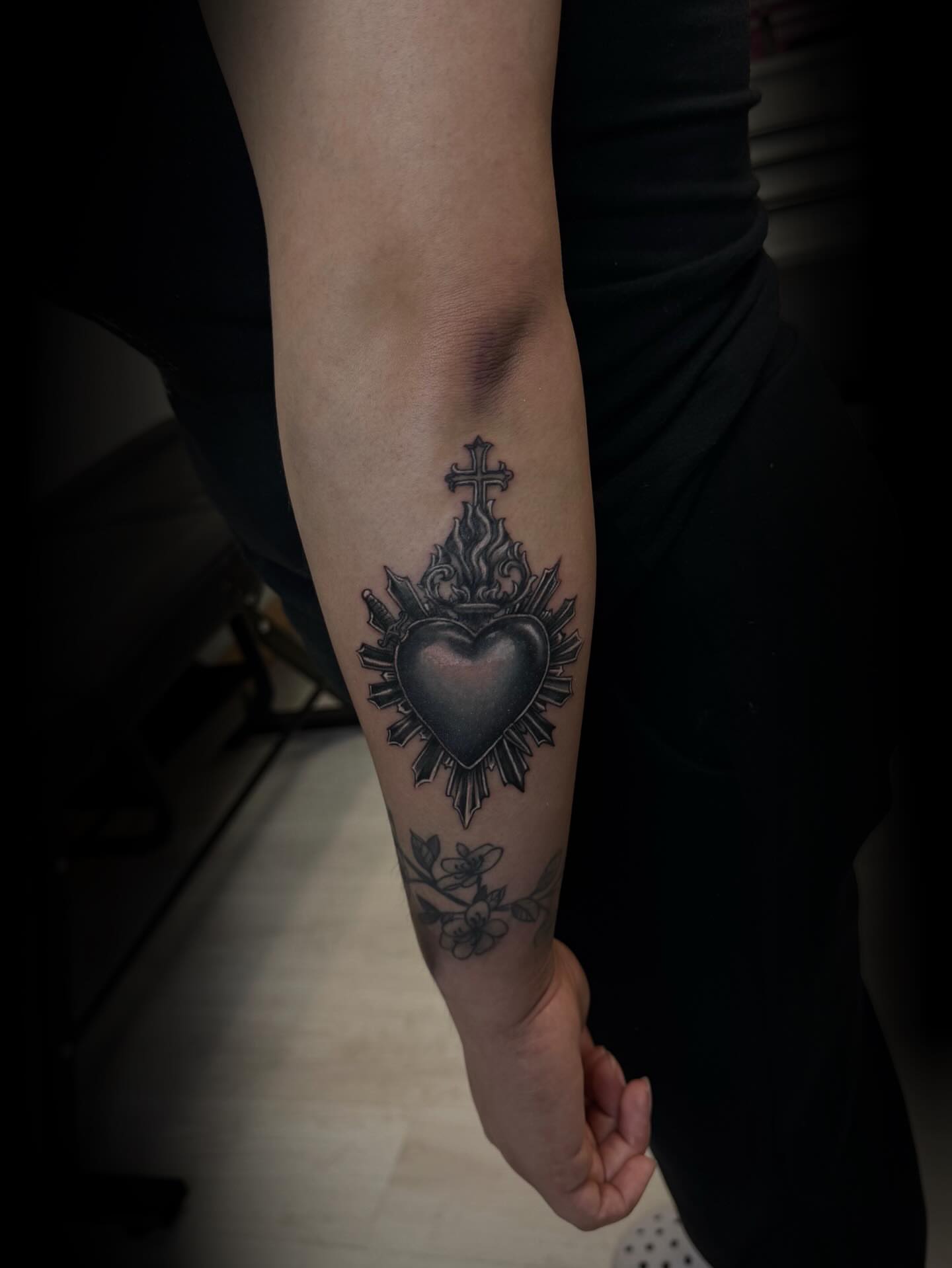 Heart with cross black and grey tattoo on the forearm by Gigi