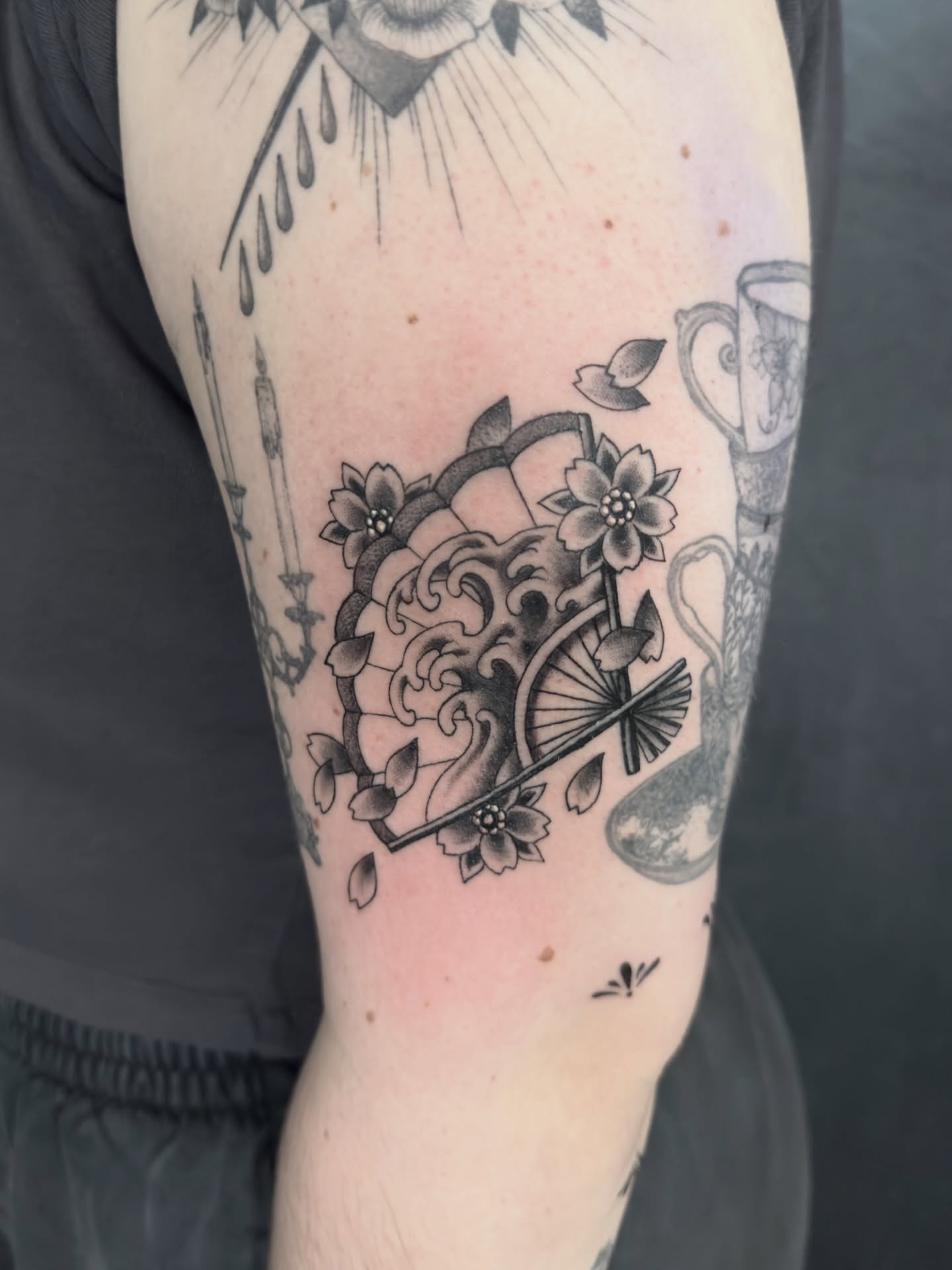 Wave and flowers black and grey tattoo on the forearm by Scott Kulikowski