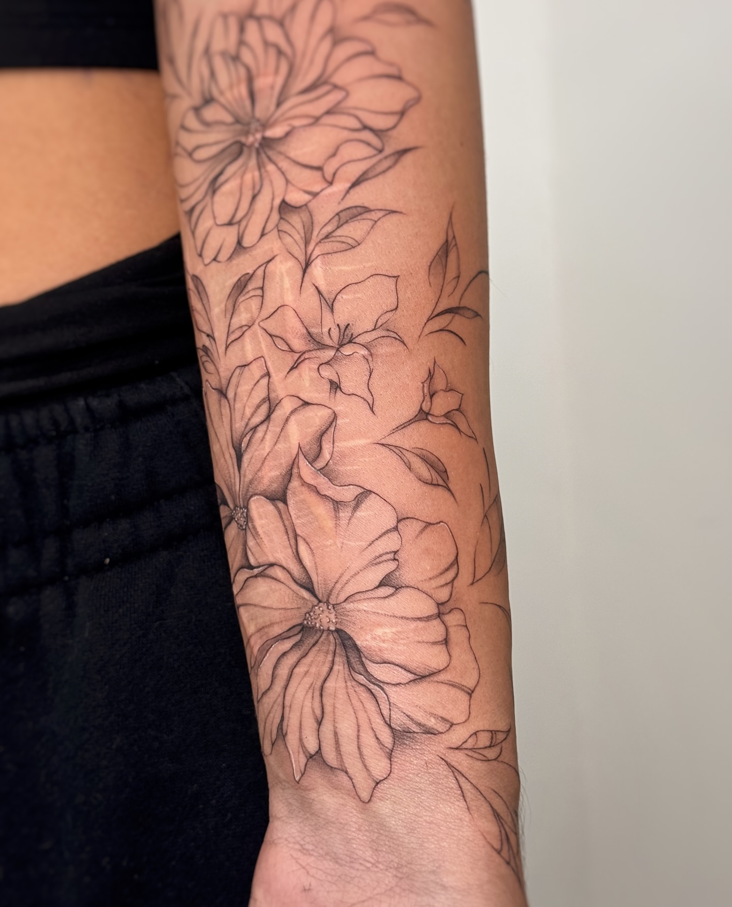 Flowers black and grey tattoo on the forearm by Gianna Rodriguez