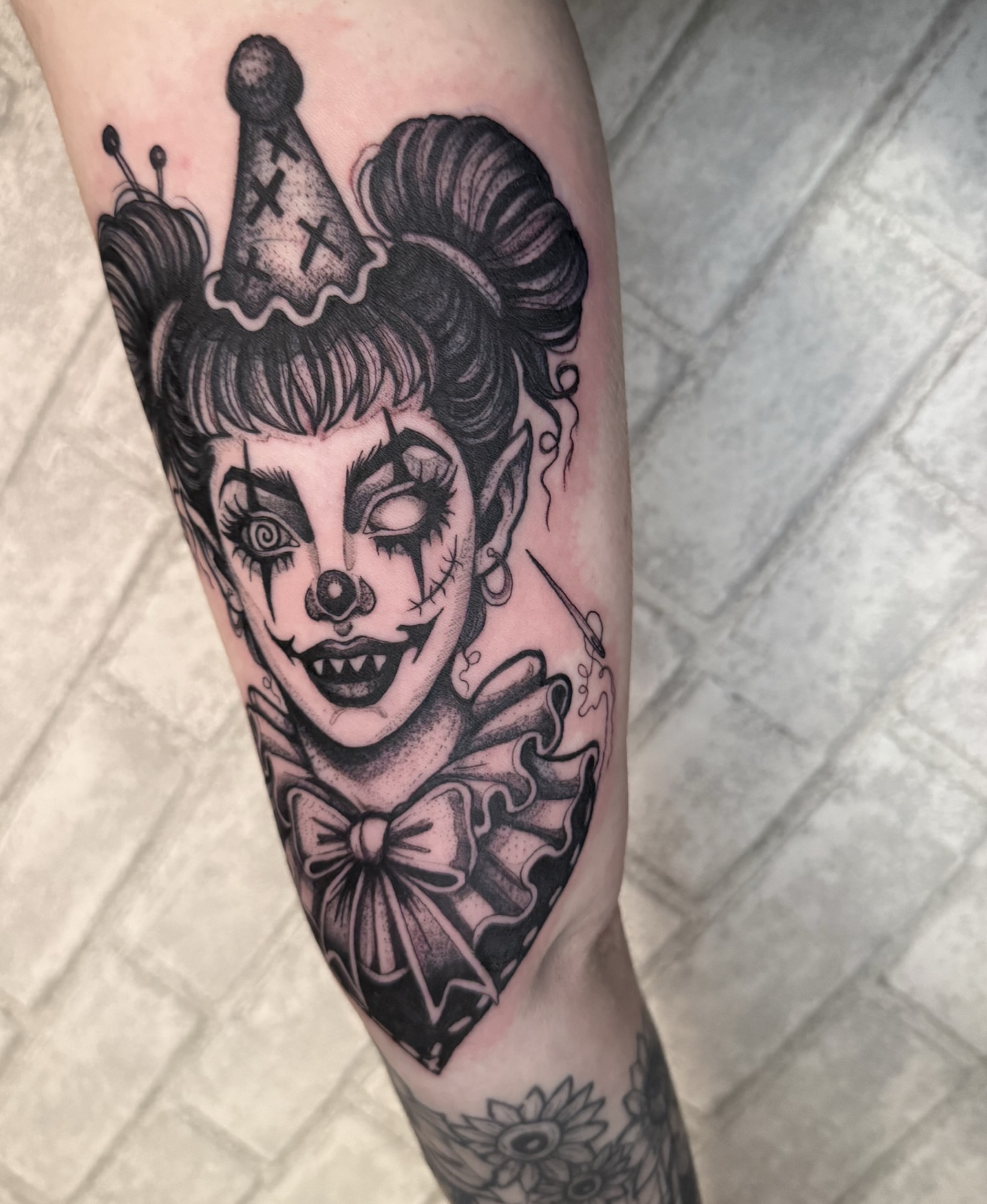 Clown black and grey tattoo on the forearm by amanda malia wega