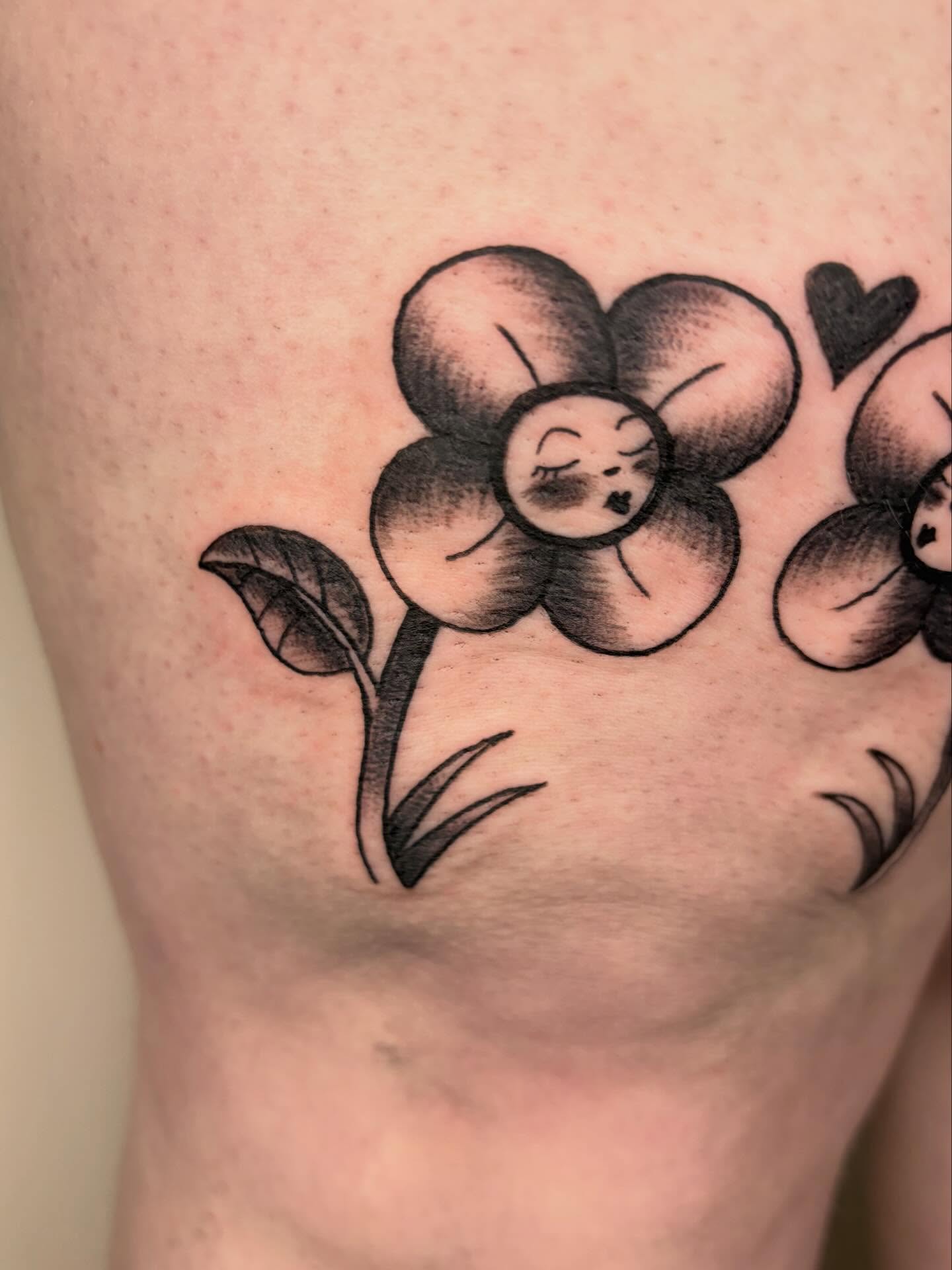 Flower with face black and grey tattoo on the thigh by Fin :