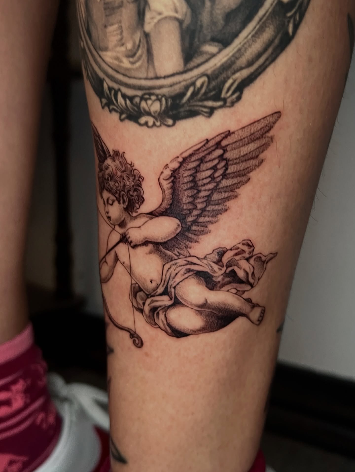 Cherub with bow black and grey tattoo on the forearm by AJ π°π· LA tattoo