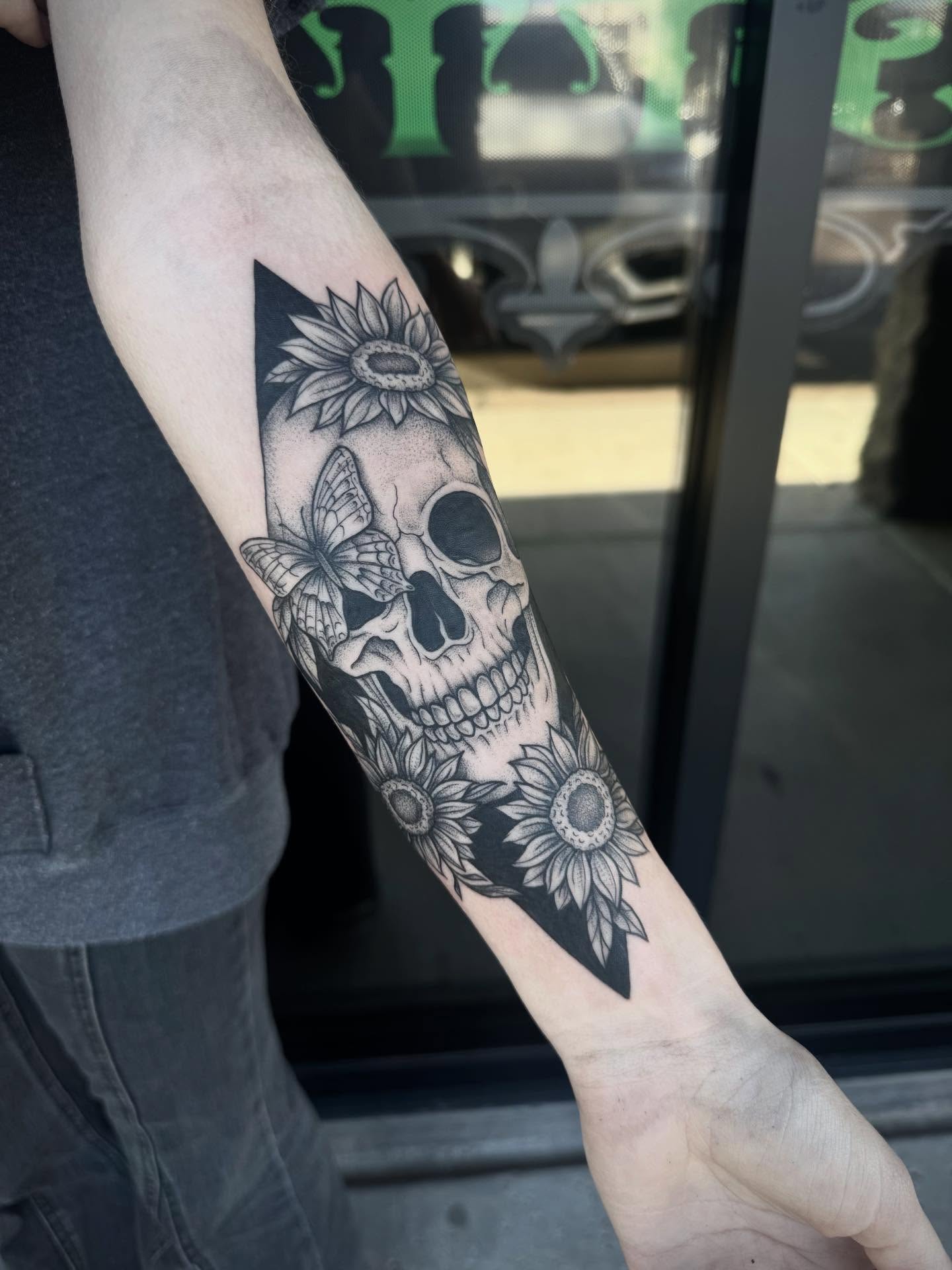 Skull and sunflowers realism tattoo on the forearm by Jianna