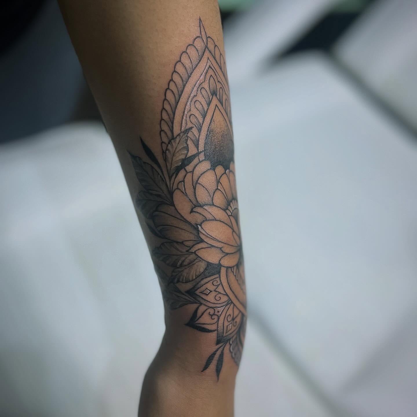 Lotus flower black and grey tattoo on the forearm by Rikki