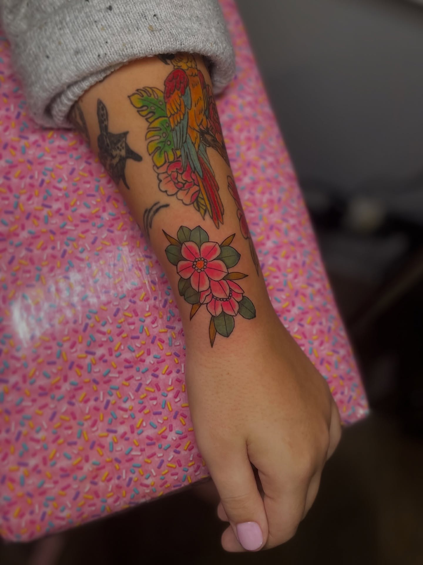 Parrot and flowers American traditional tattoo on the forearm by Liv