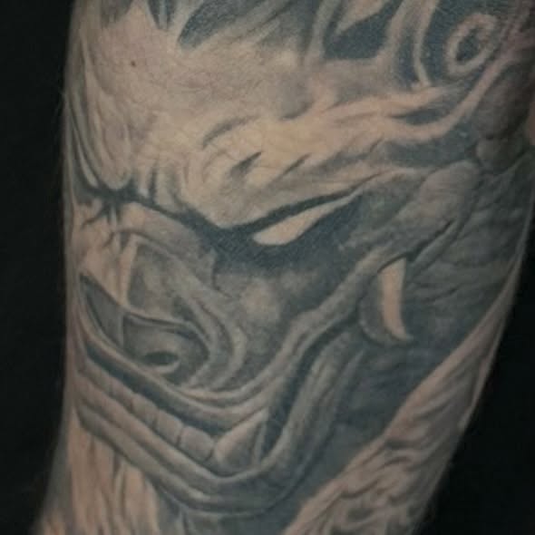 Mask black and grey tattoo on the forearm by Matthew Doherty