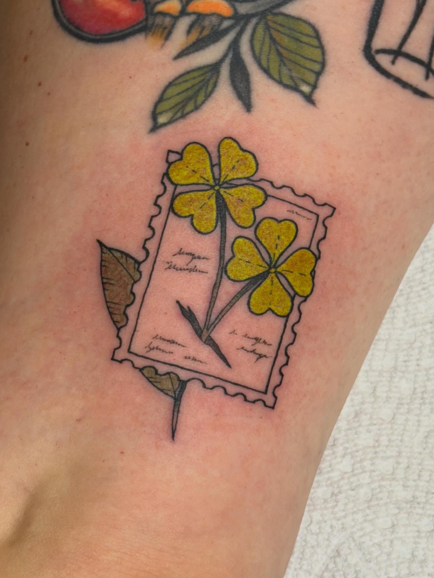 Clover and postage stamp American traditional tattoo on the forearm by Sophia, New Carlisle, Ohio