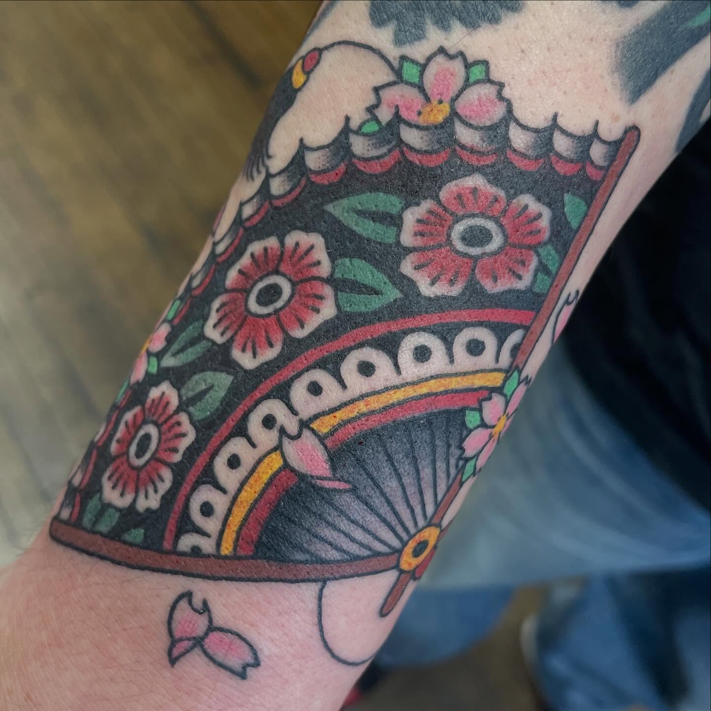 Fan and flowers American traditional tattoo on the forearm by Haley McMahon