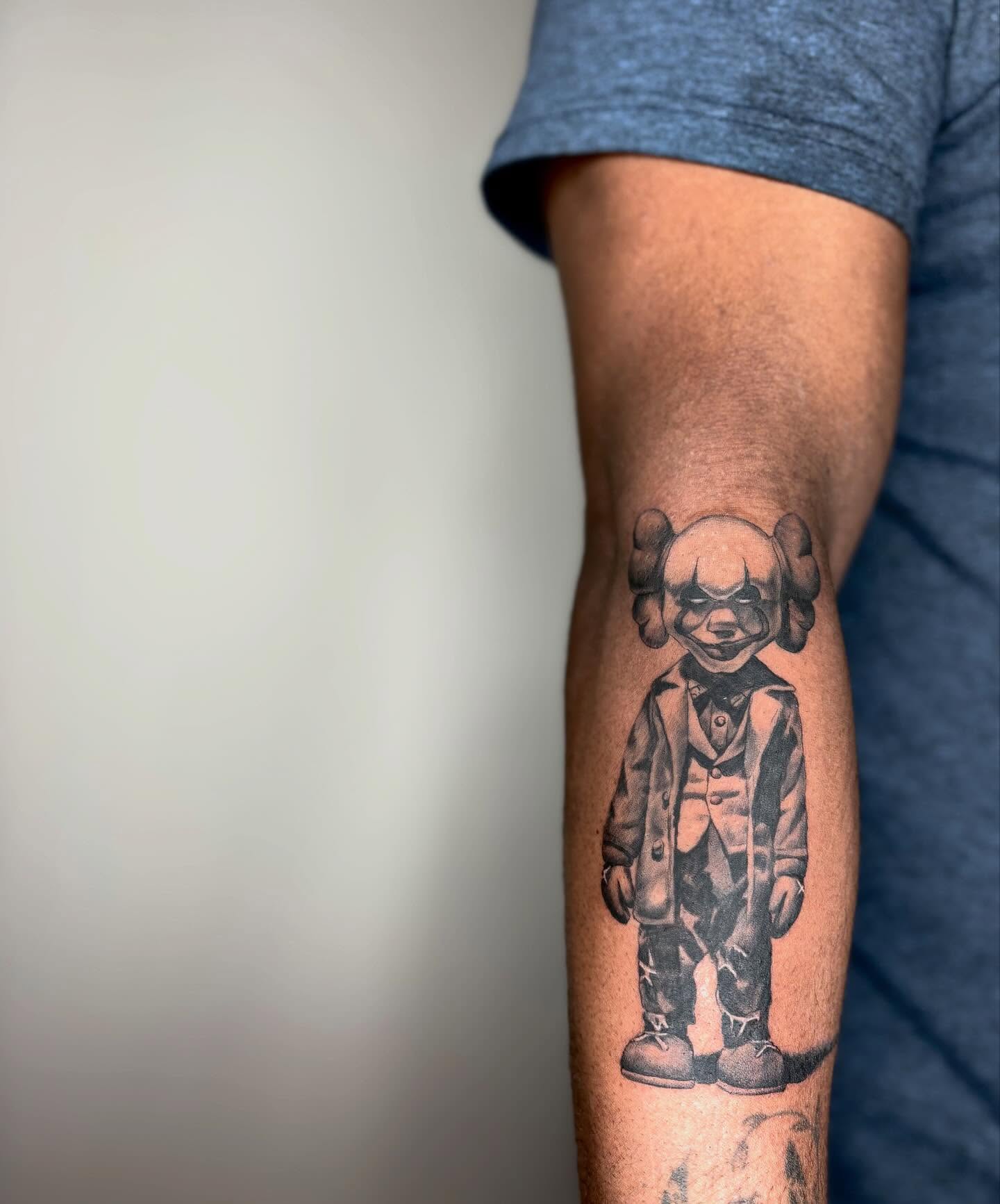 Pennywise black and grey tattoo on the forearm by Koolz