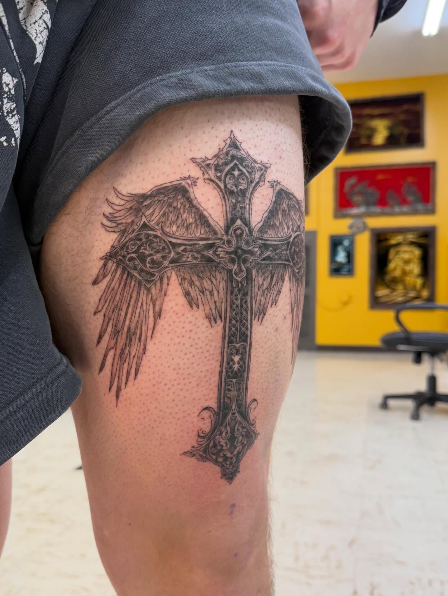 Cross with wings dotwork tattoo on the thigh by Levi Sawdon, Everett, Washington