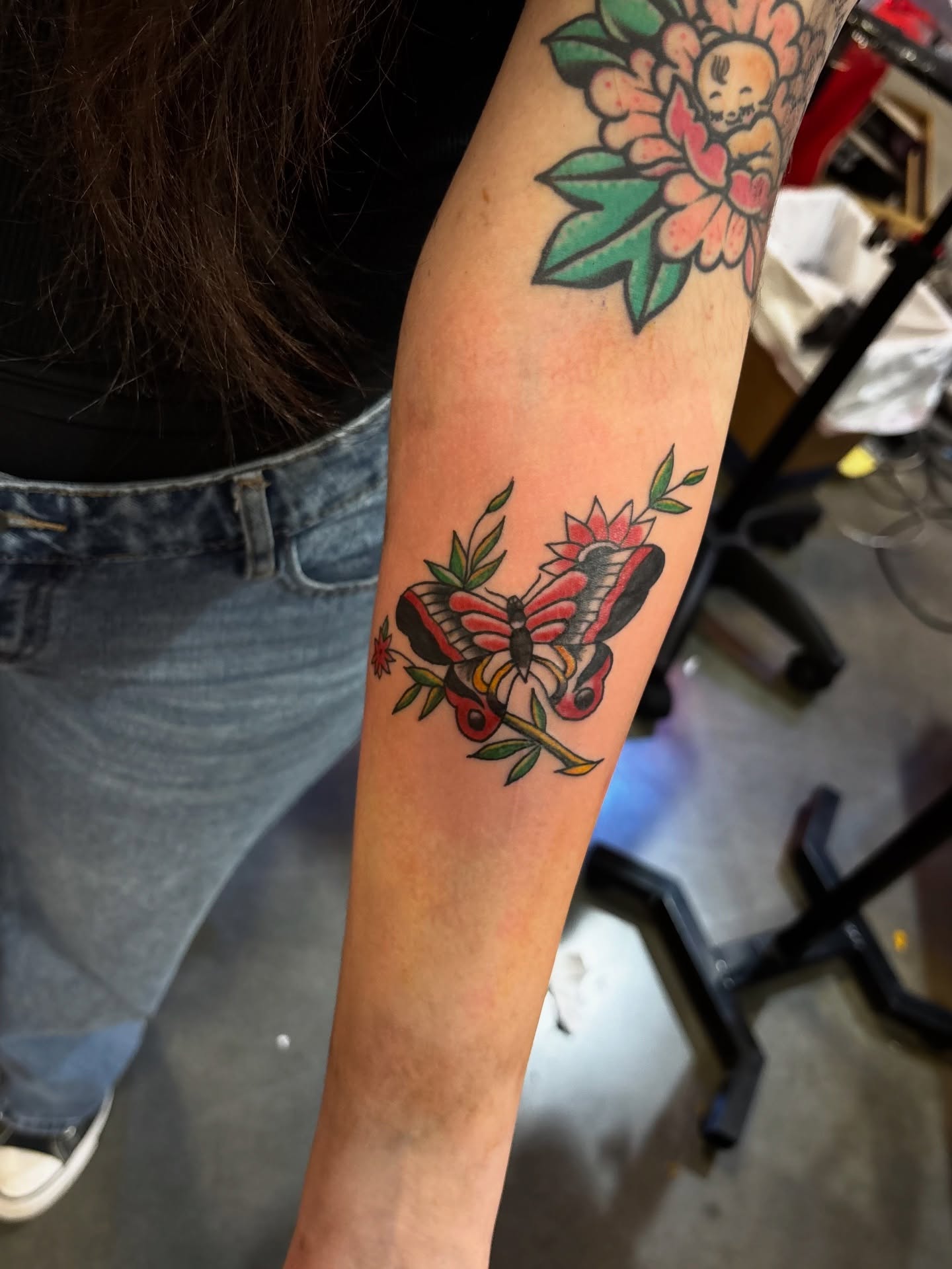 Butterfly and flowers American traditional tattoo on the forearm by Nyah Ramirez