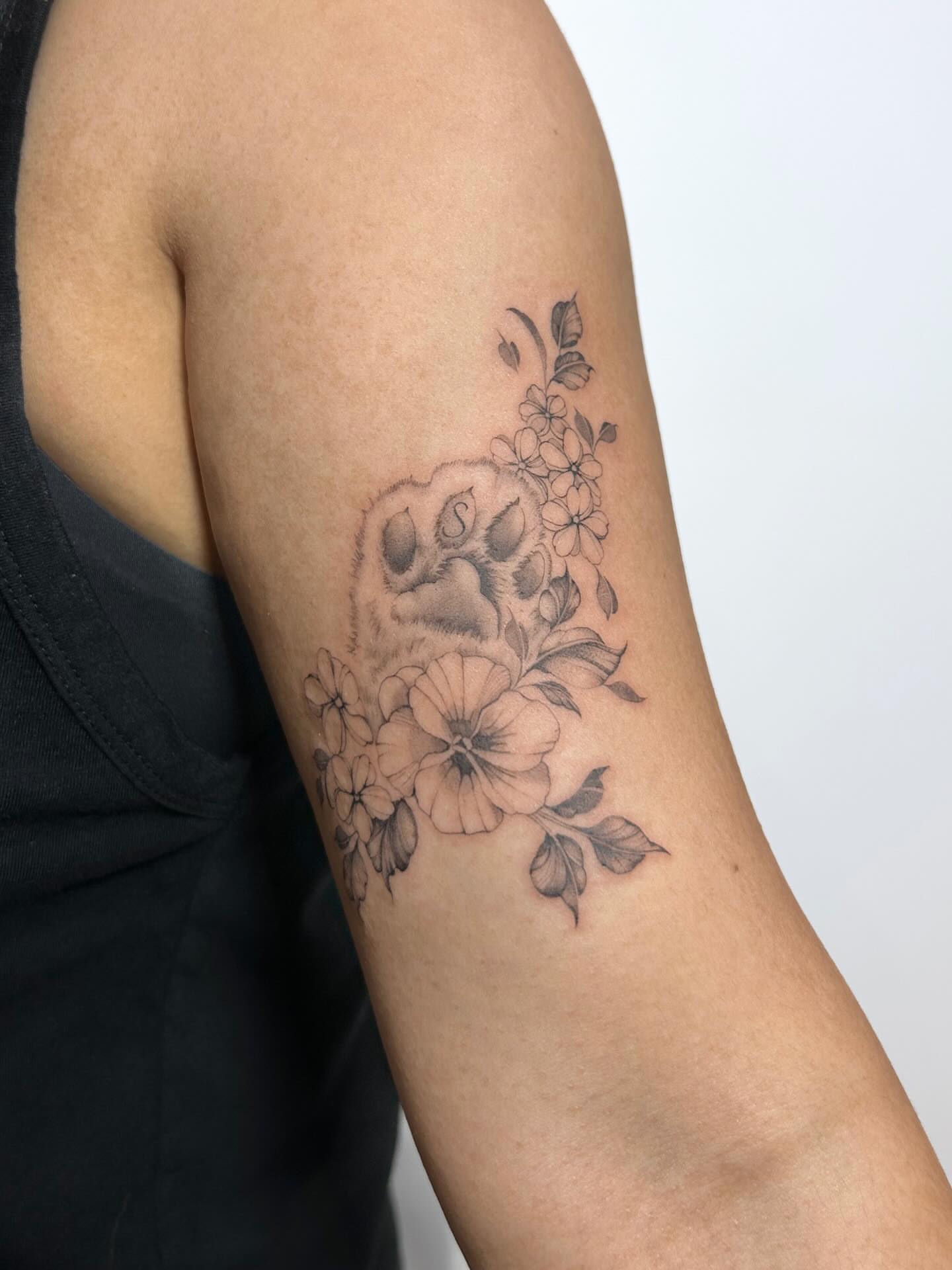 Skull and flowers black and grey tattoo on the forearm by Chloe