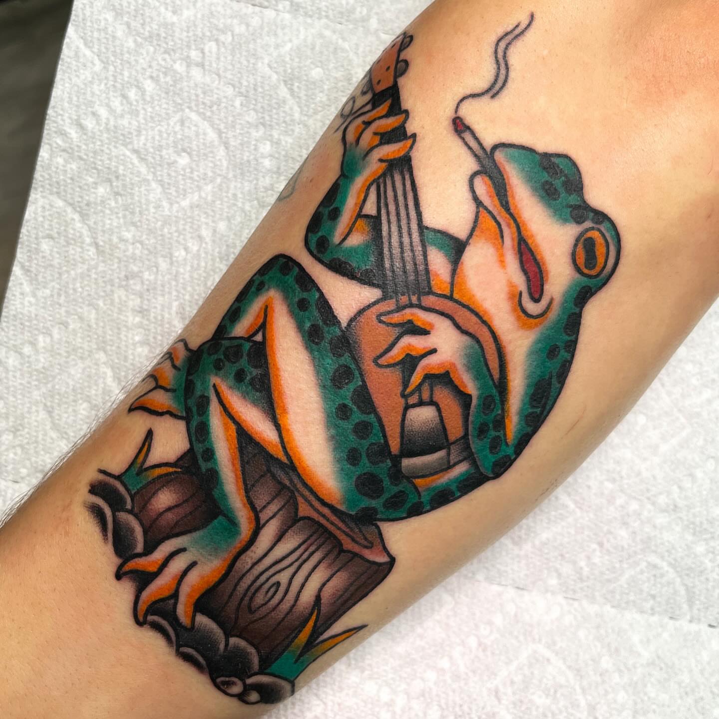Frog playing guitar American traditional tattoo on the forearm by Sky G, Colorado Springs, Colorado
